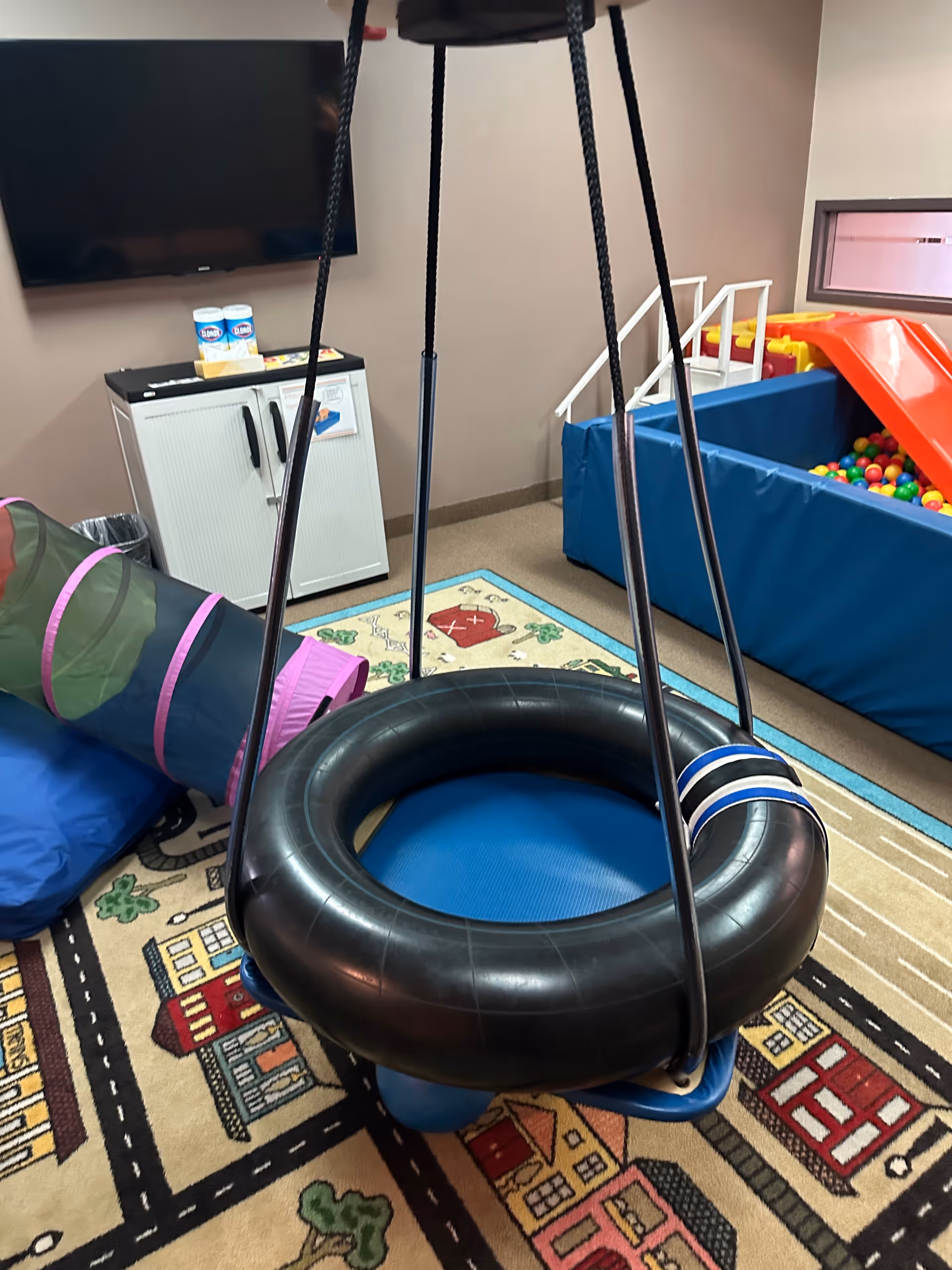 Indoor play area in the facility with a circular swing and ball pit.