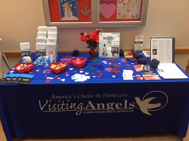 Promotional information table for Visiting Angels in an interior hallway with brochures