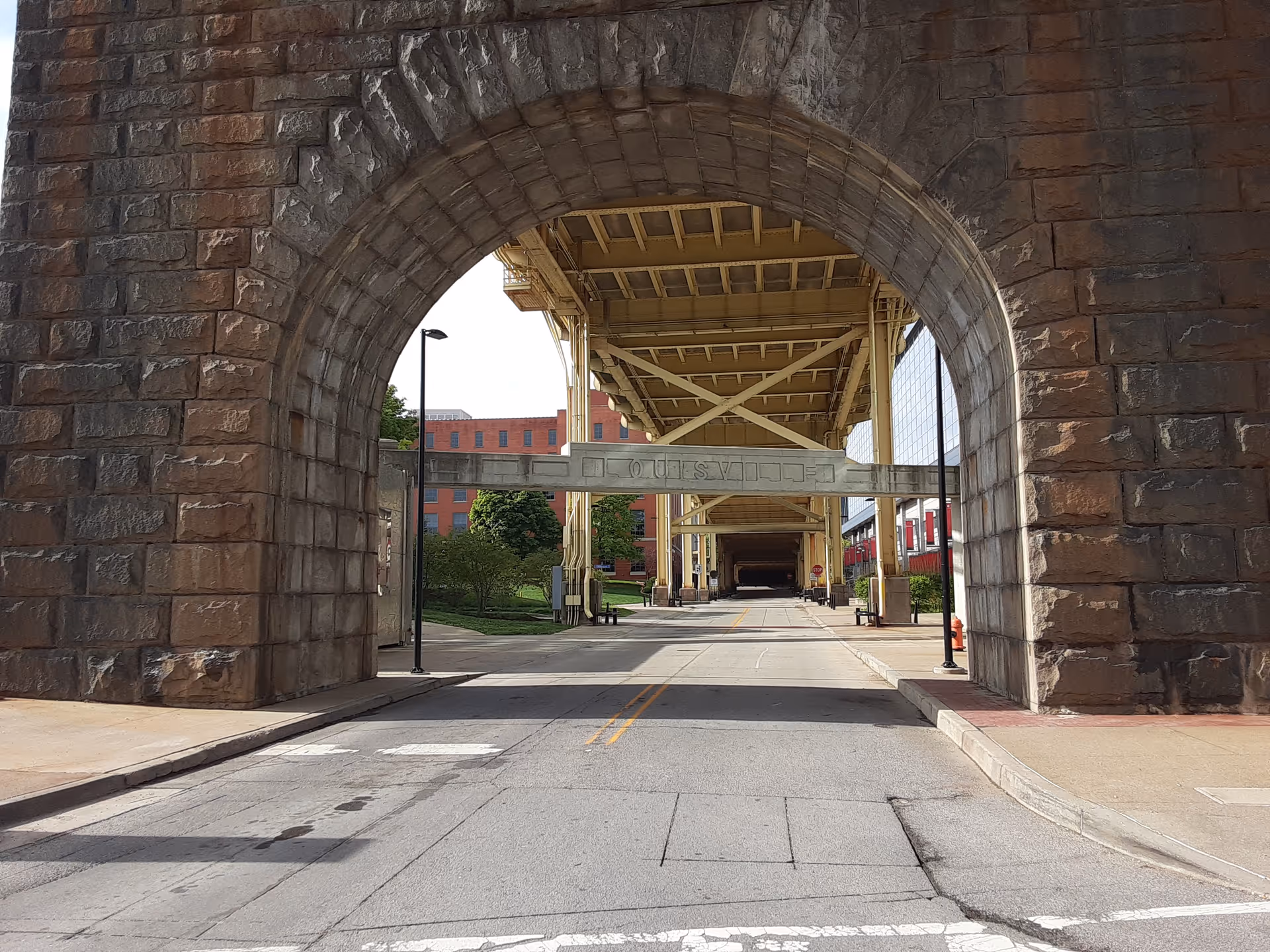 Stone archway over a street with an elevated walkway and surrounding buildings.