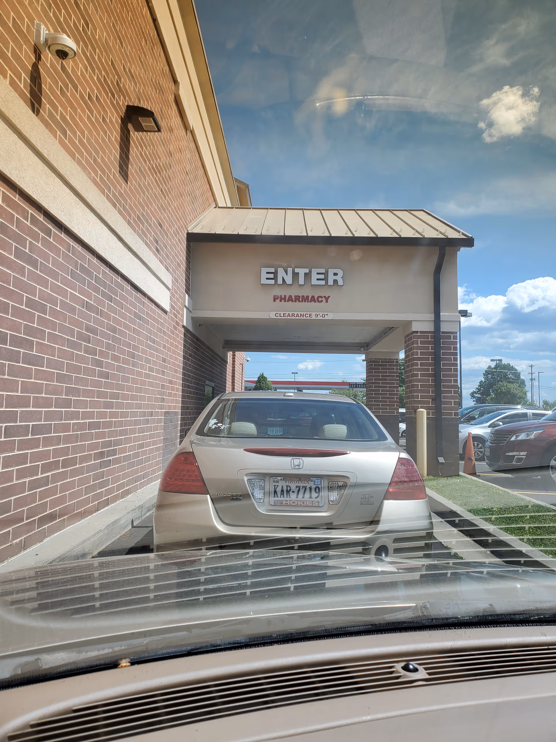 Brick exterior of a building with a covered entrance labeled ENTER PHARMACY and a parked car.