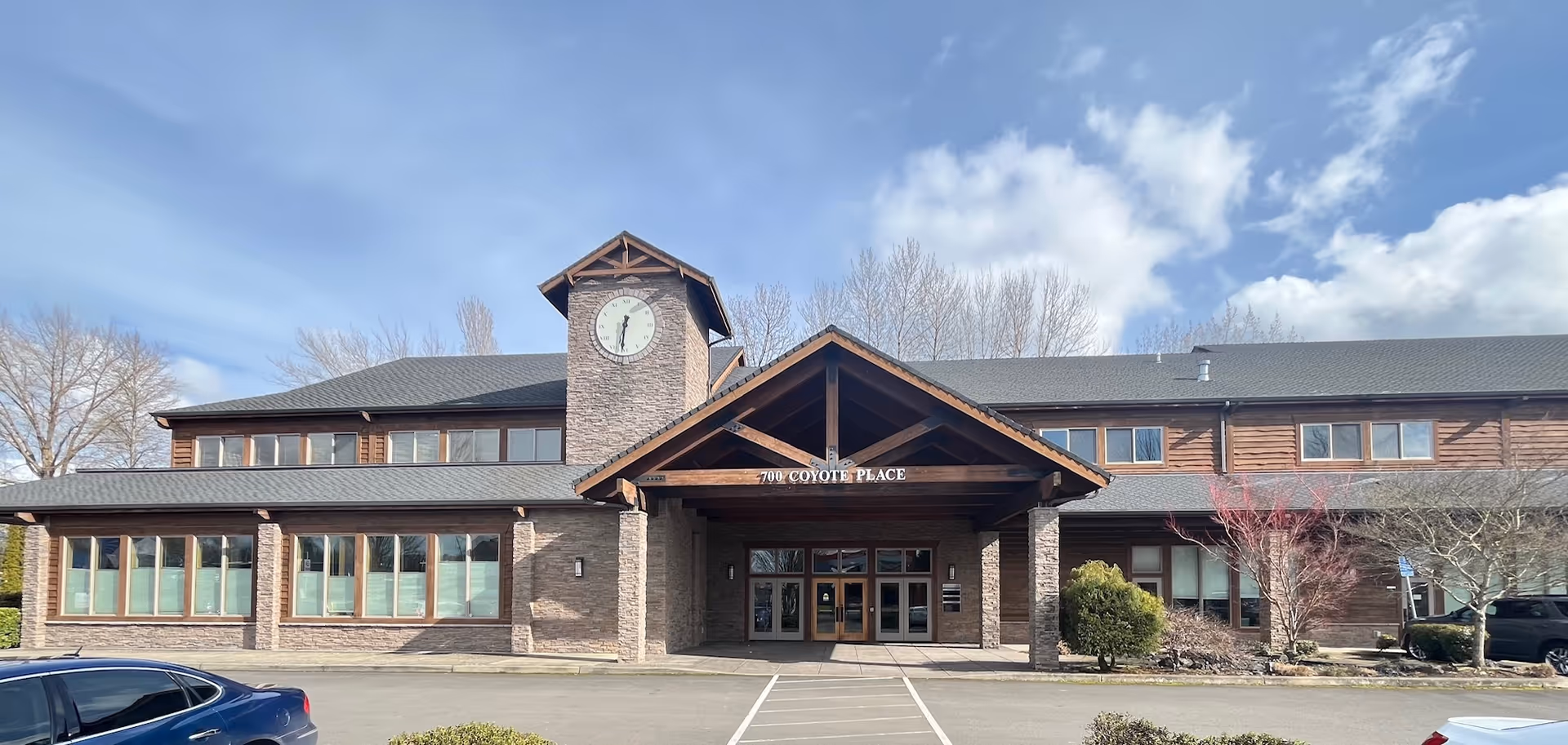 Exterior view of a brick senior home care facility with clock tower and covered entrance.