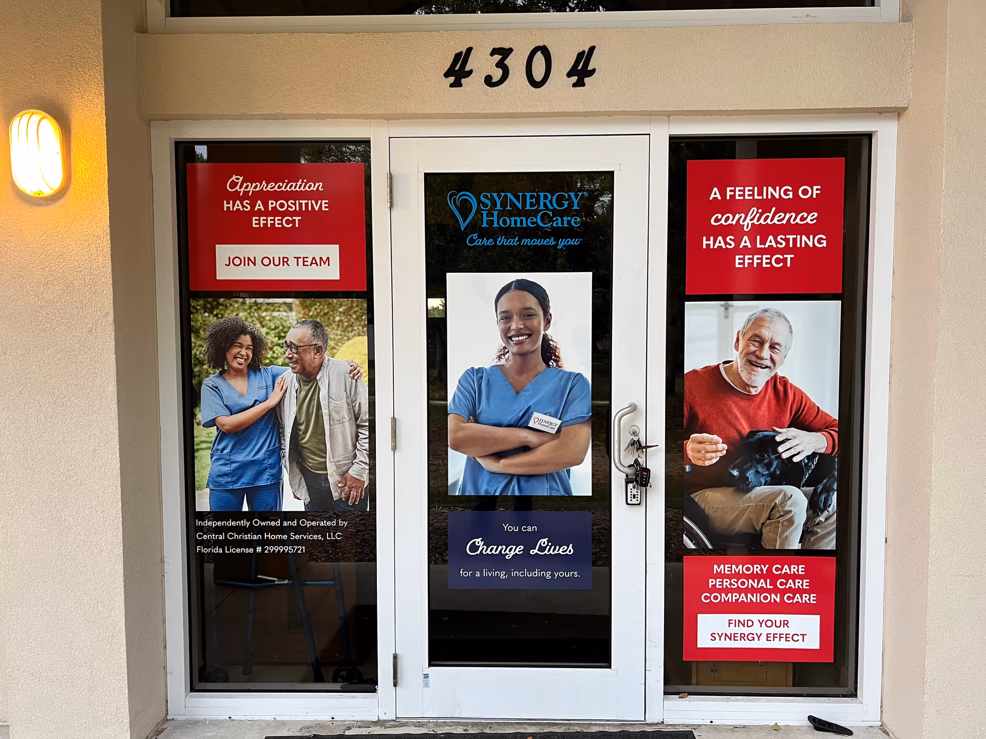 Glass entrance doors of a Synergy HomeCare facility with posters featuring caregivers and seniors.