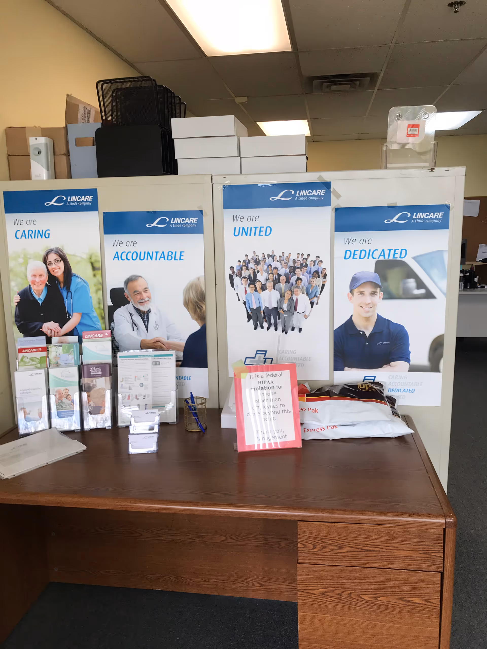 Desk area with Lincare banners, brochures, and office supplies.