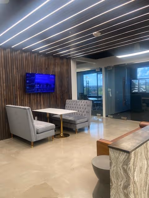 Modern senior living lounge with two gray armchairs, a small table, and a wall-mounted TV.