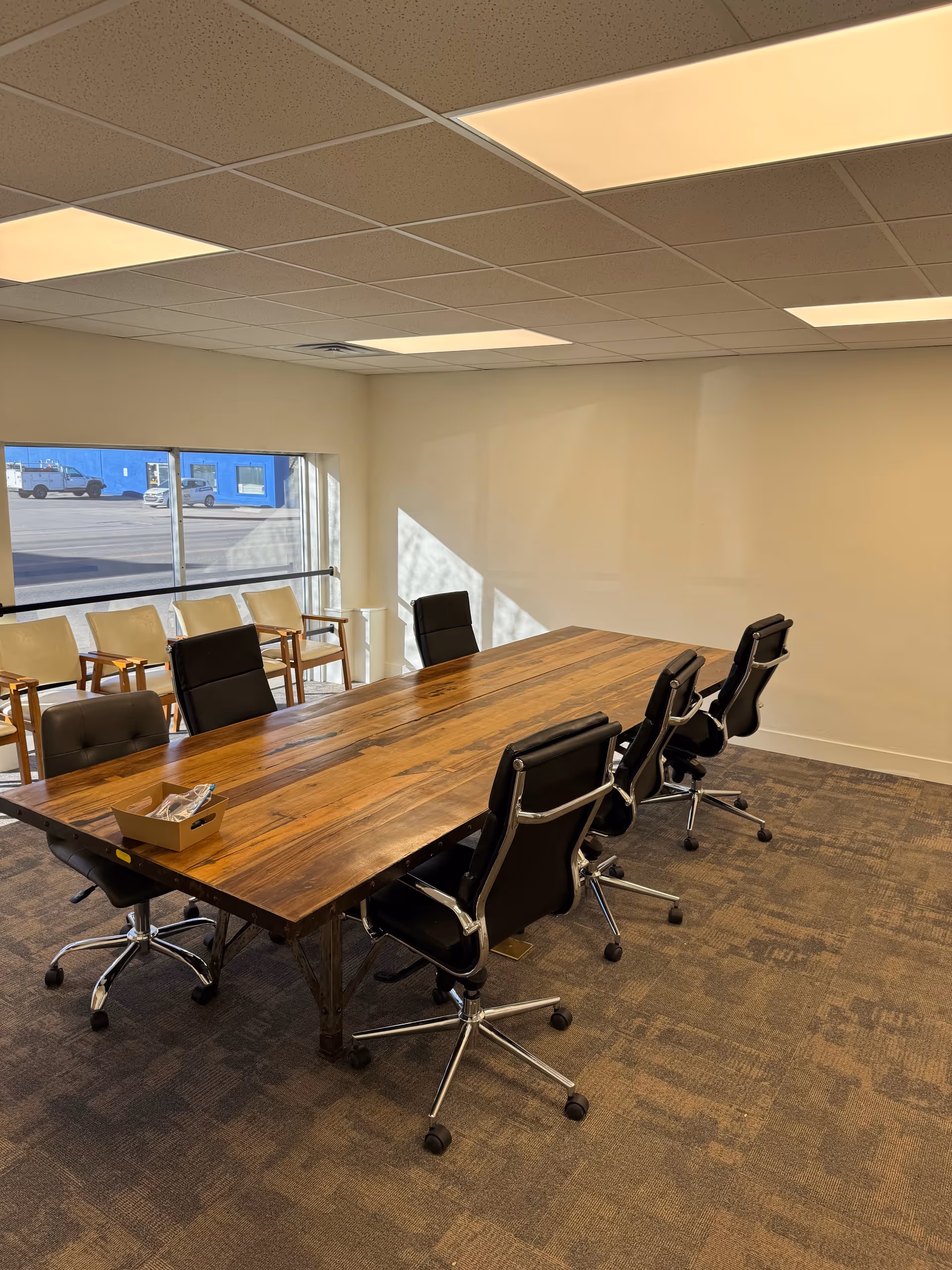 Large wooden conference table with black chairs in a bright meeting room
