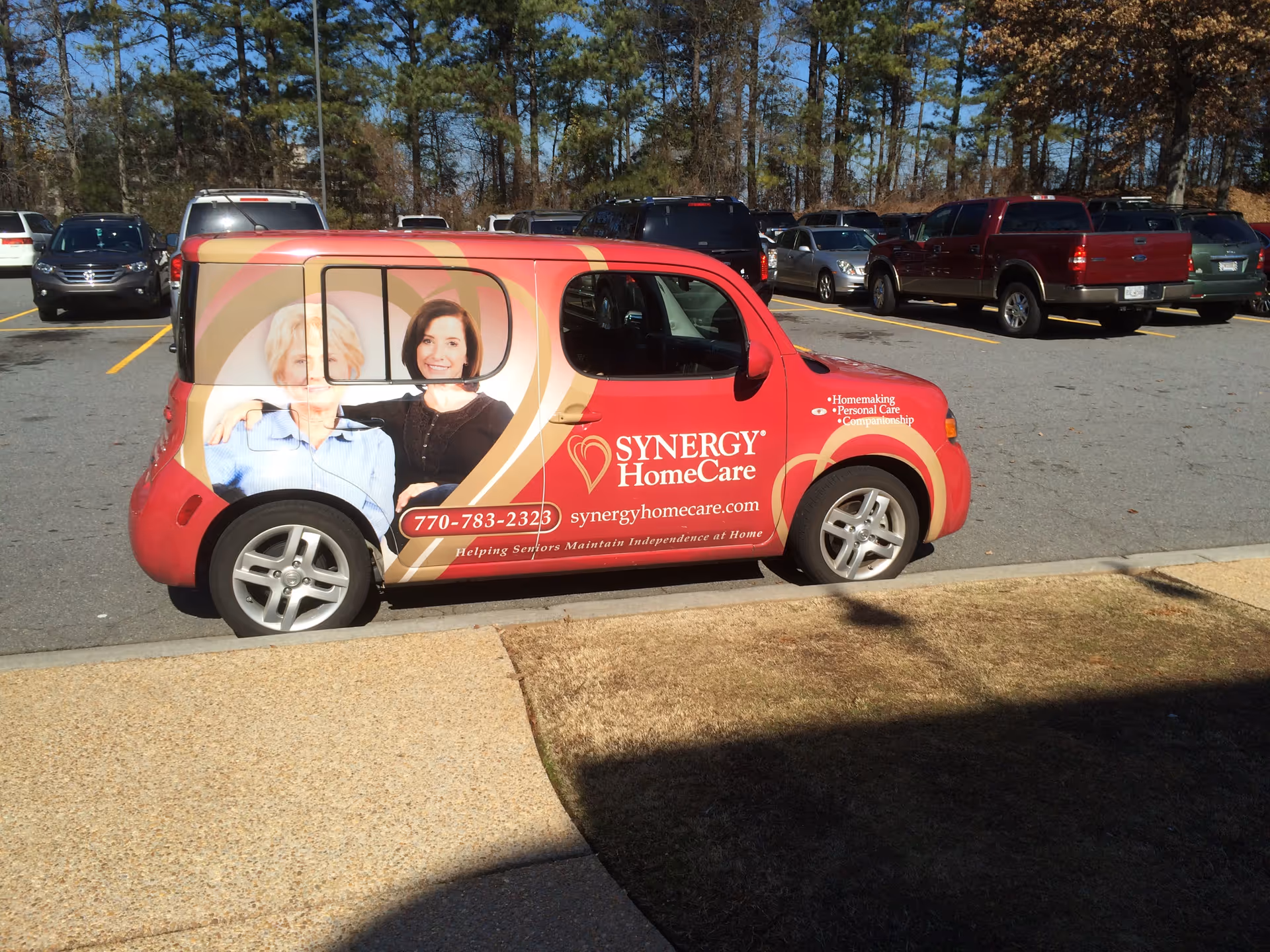 Red SYNERGY HomeCare van with branding parked in a lot.