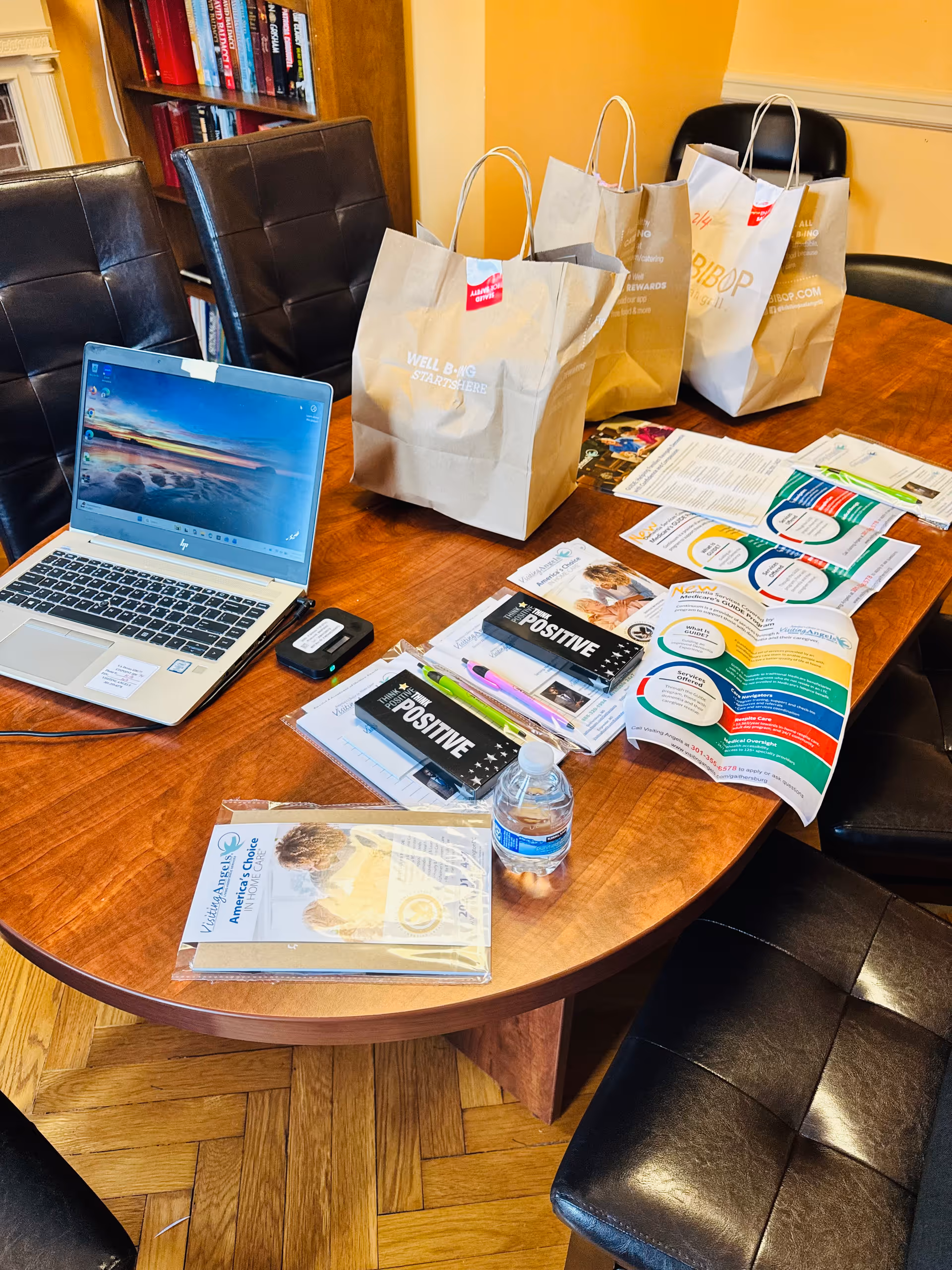 Conference table in a home care office with laptop, brochures, and gift bags.