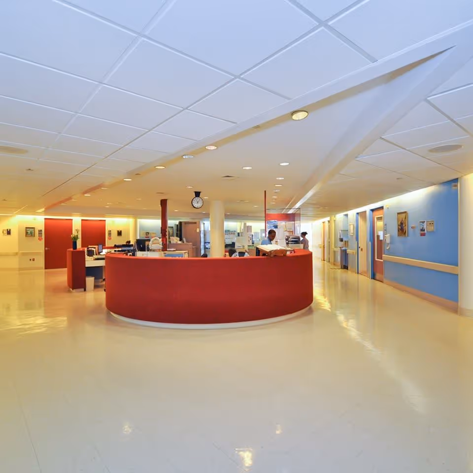 Interior of Calvary Hospital lobby featuring a curved red reception desk and bright overhead lighting.