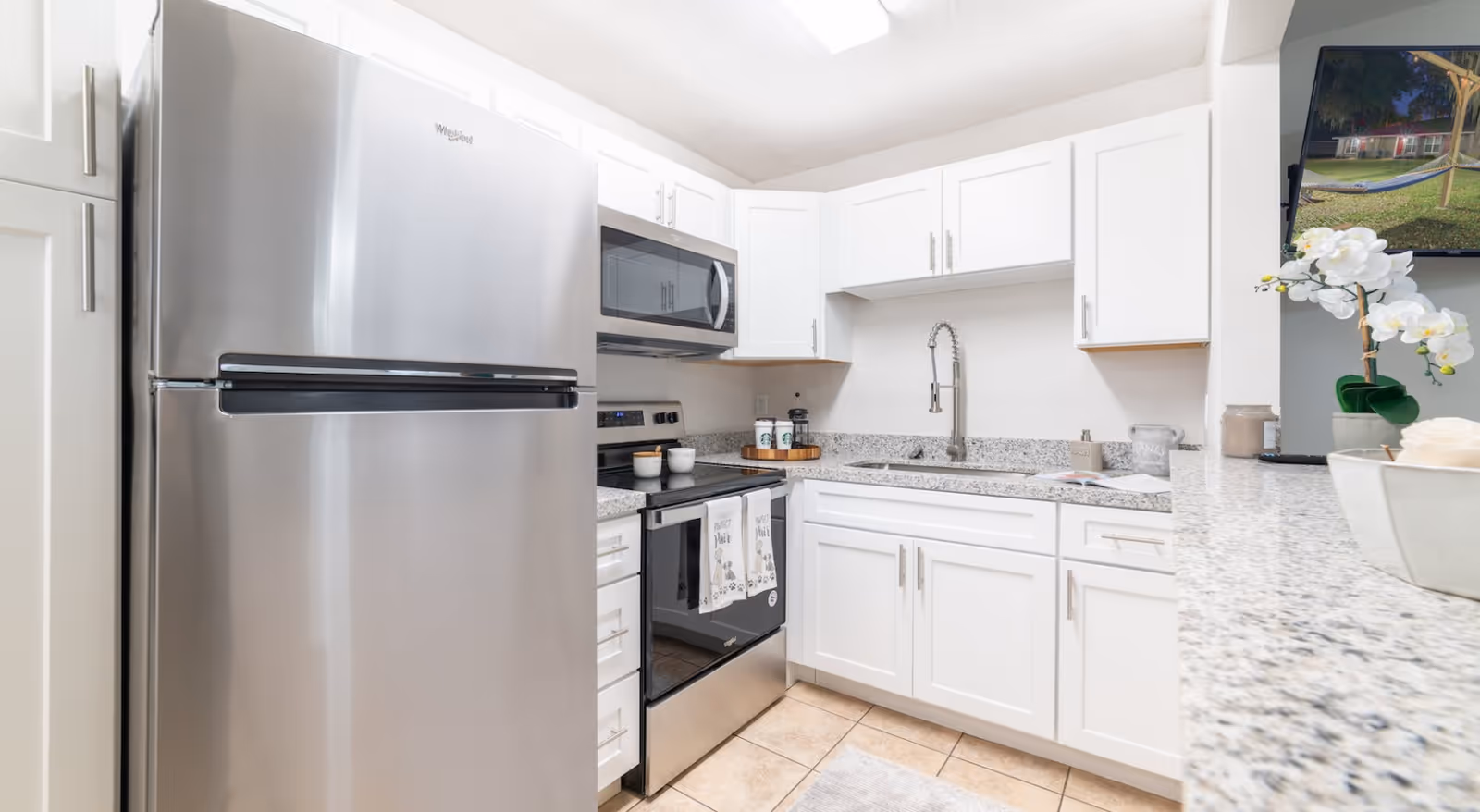 Bright, modern kitchen with white cabinets, stainless steel appliances, and granite countertops.