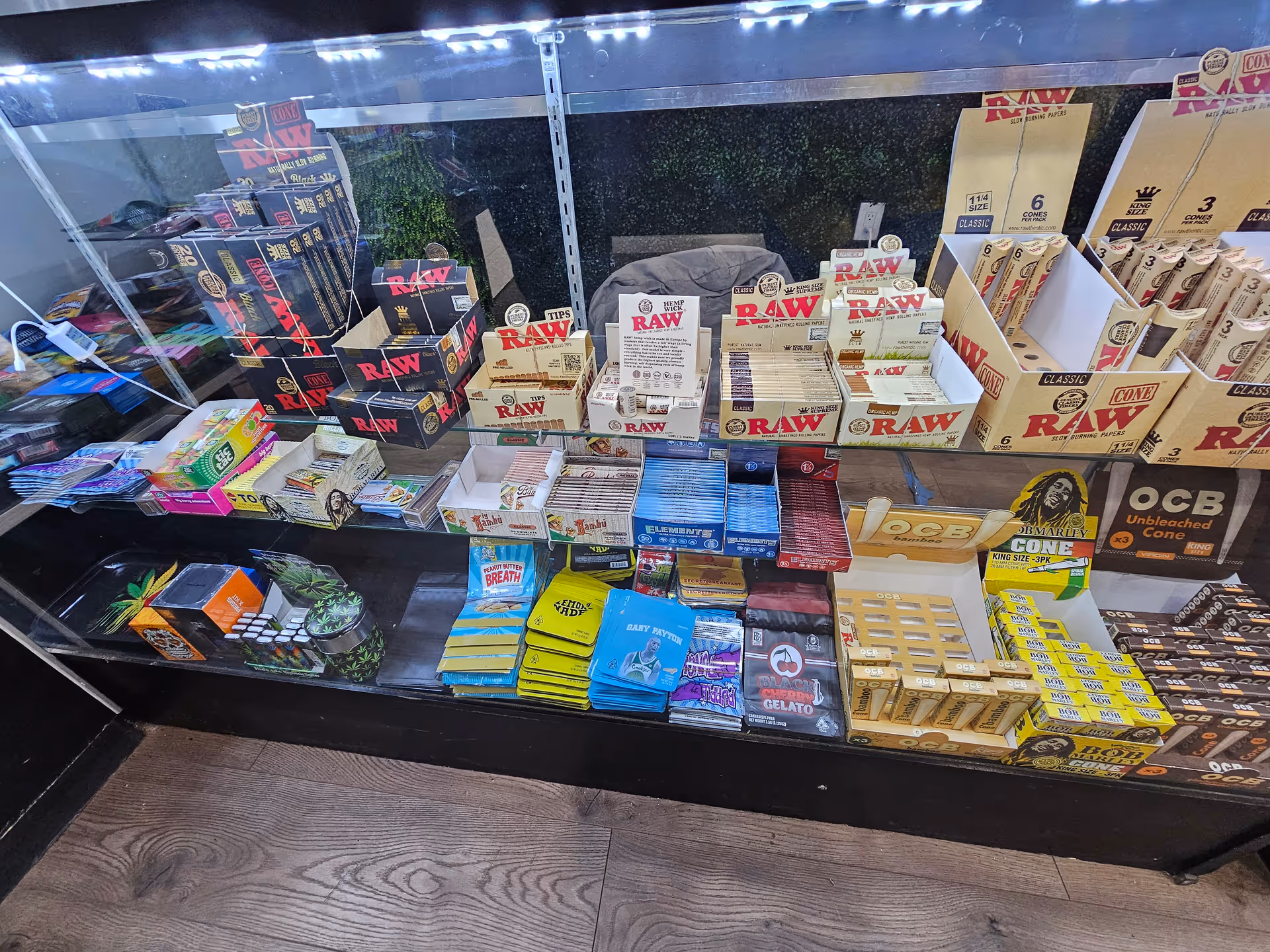 Glass display case filled with assorted cannabis products and packaging on shelves.