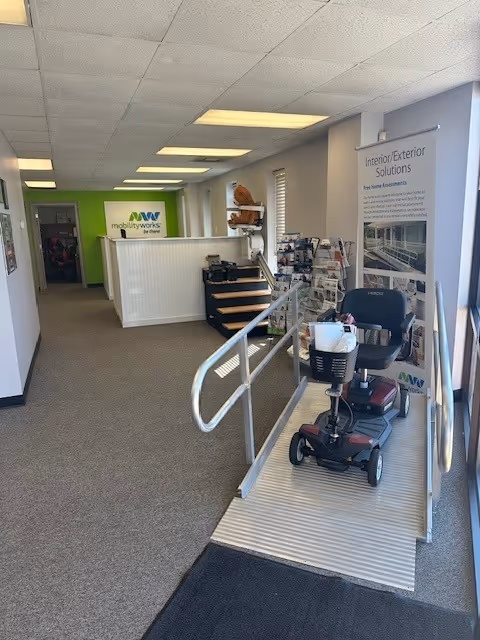 Interior MobilityWorks lobby with a scooter on a ramp near the reception desk.