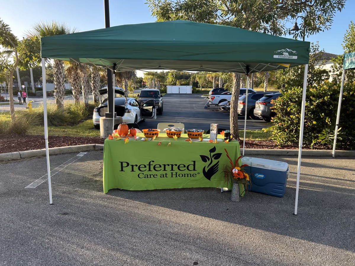 Green canopy tent over a table with pumpkins and a Preferred Care at Home banner.