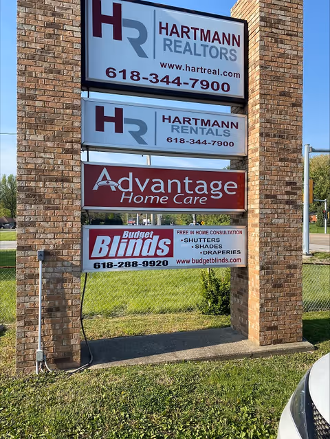 Tall brick sign pillar displaying Advantage Home Care and other business signs outdoors.