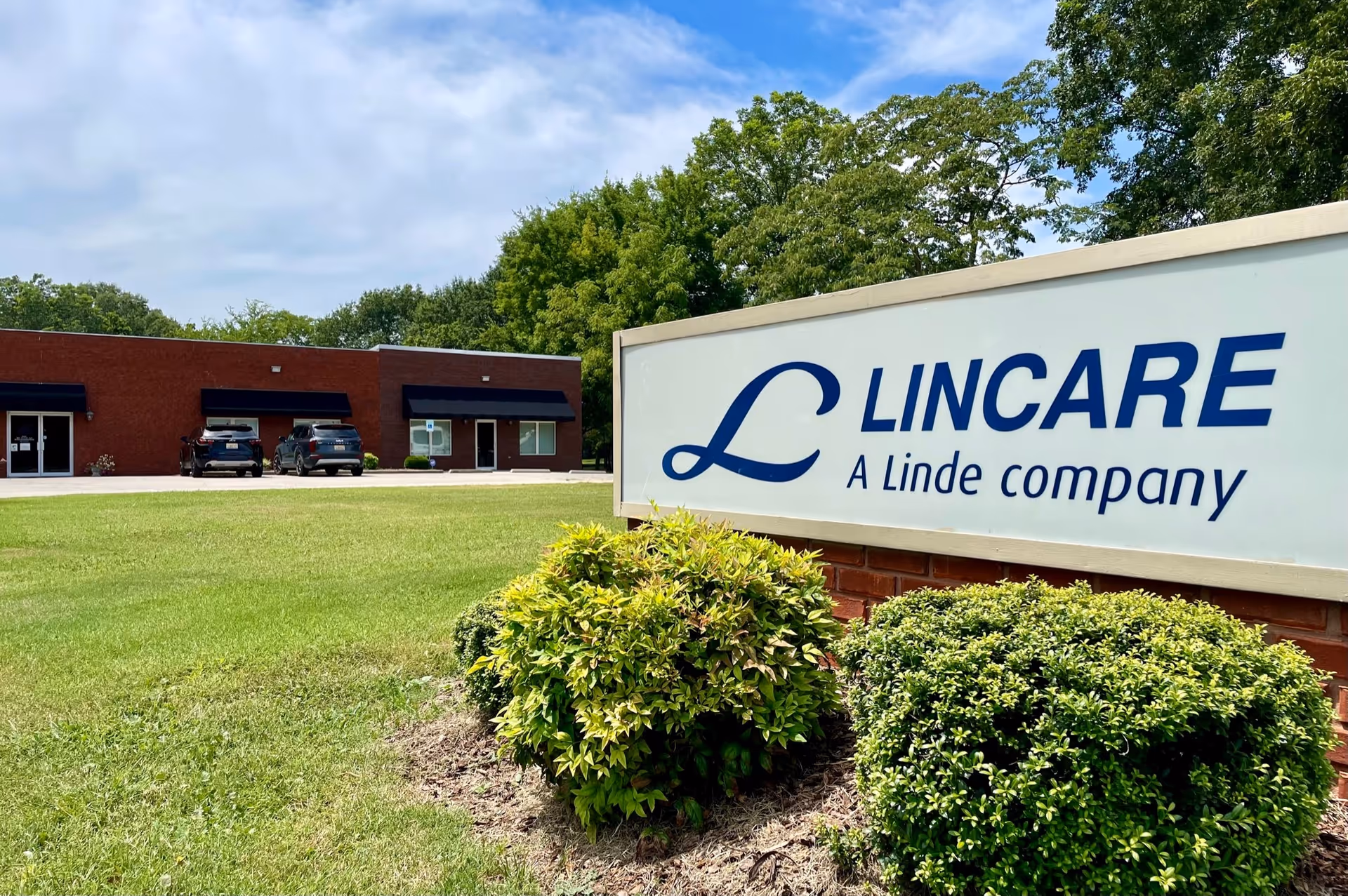 Exterior view of a LINCARE facility with a large sign and manicured shrubs.