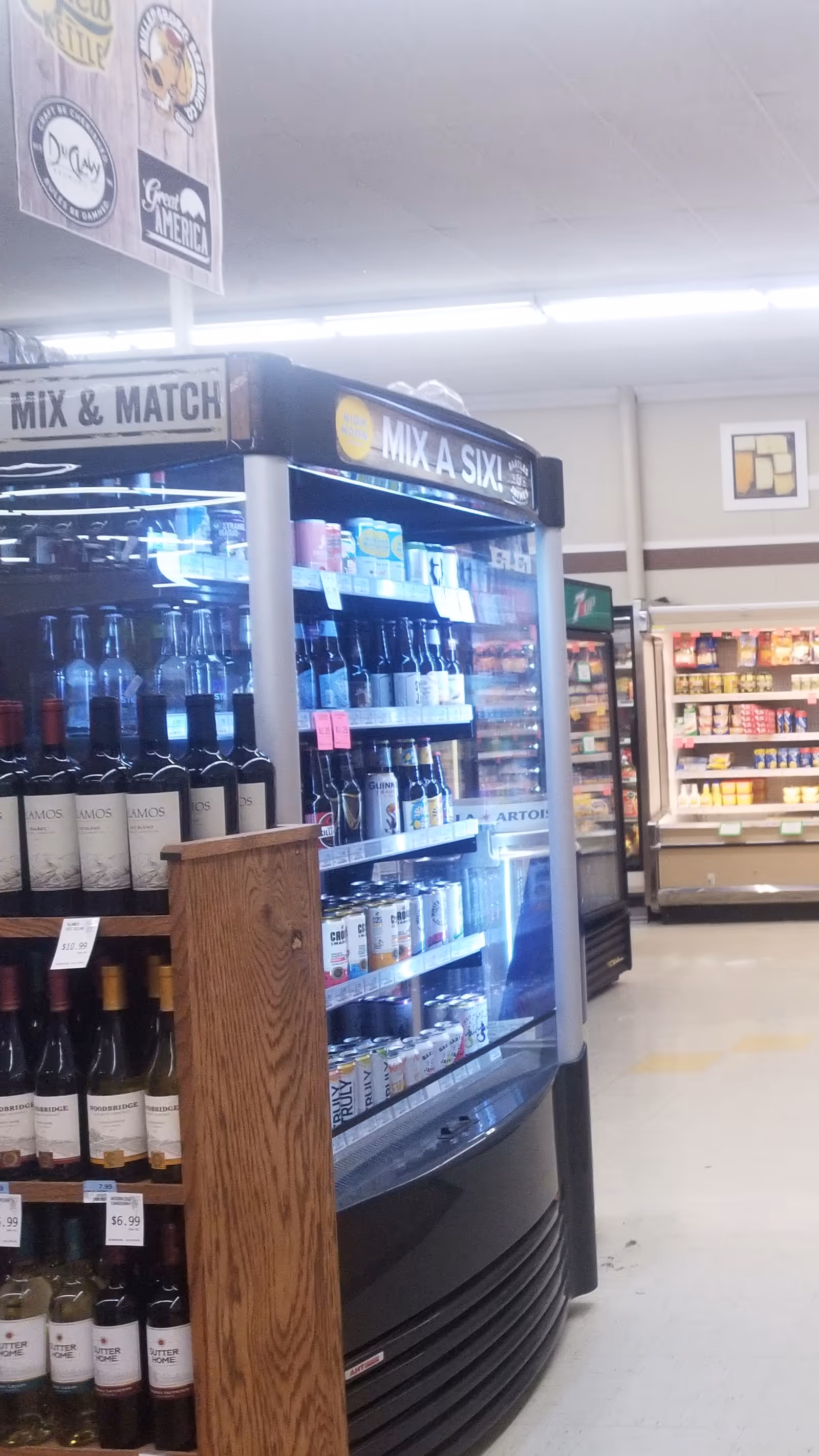 Inside Discount Drug Mart, a refrigerated alcohol display with shelves and signage.