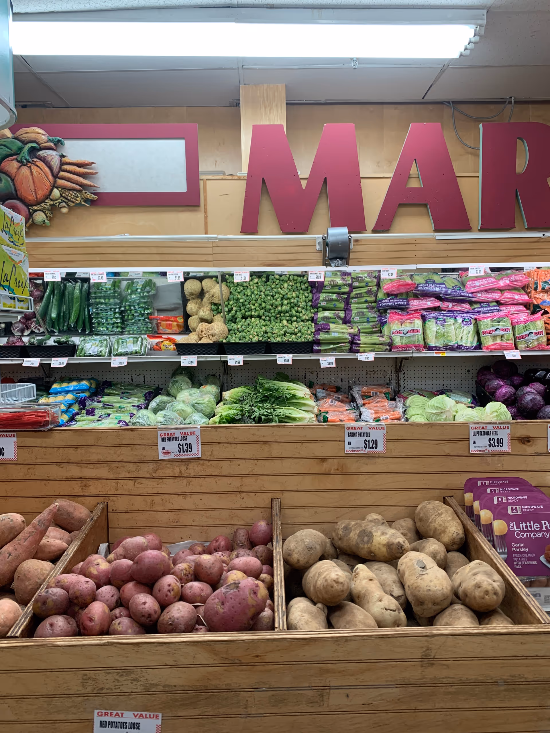 Produce section of a grocery store with crates of potatoes and other vegetables.