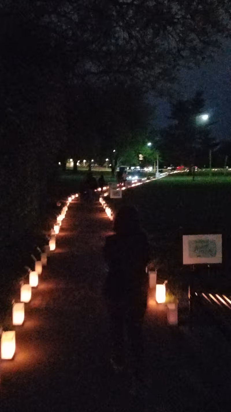 Nighttime outdoor path lined with glowing candles, guiding along a dark walkway.