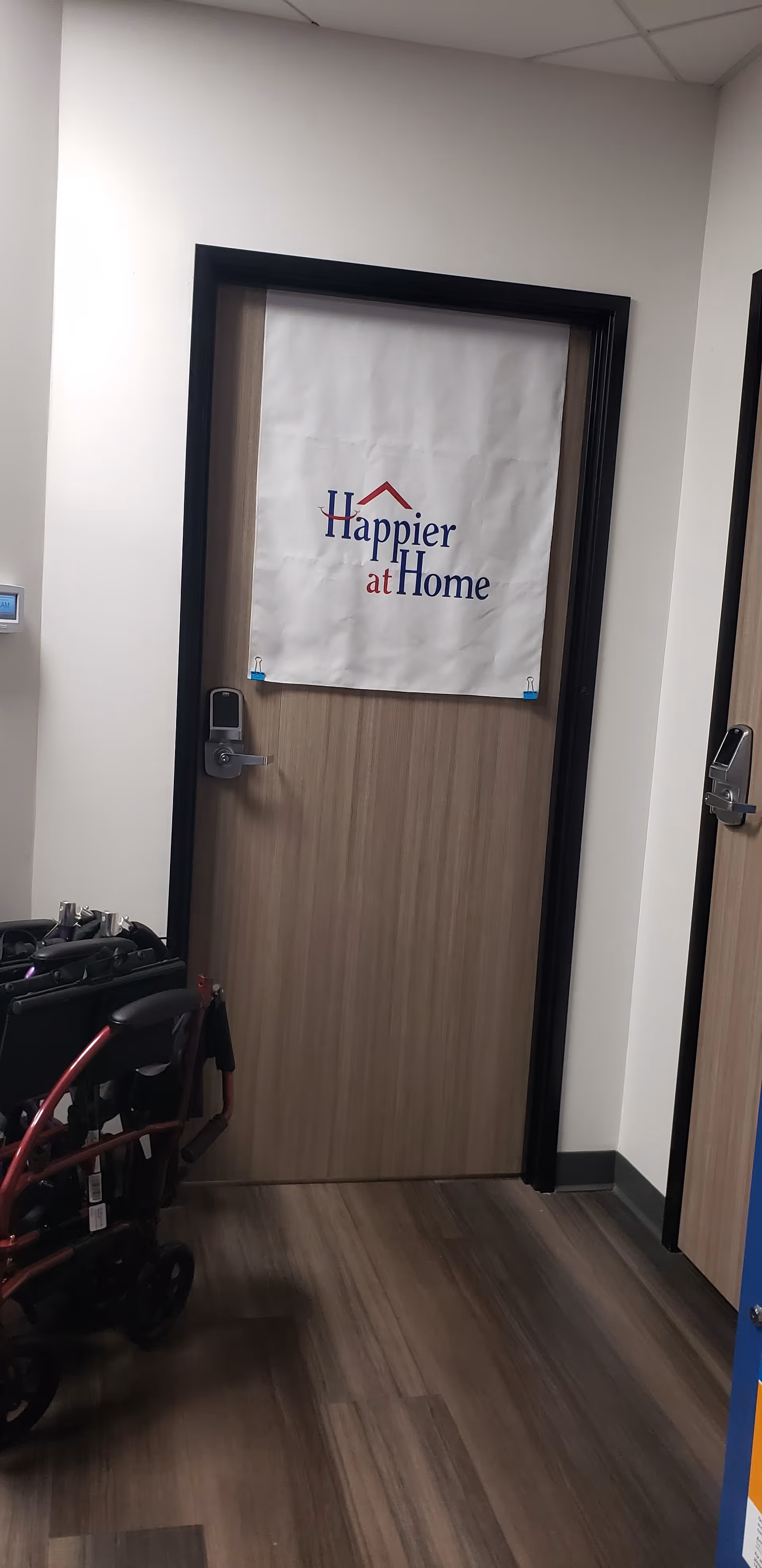 Interior hallway with a door covered by a Happier at Home banner and a wheelchair nearby