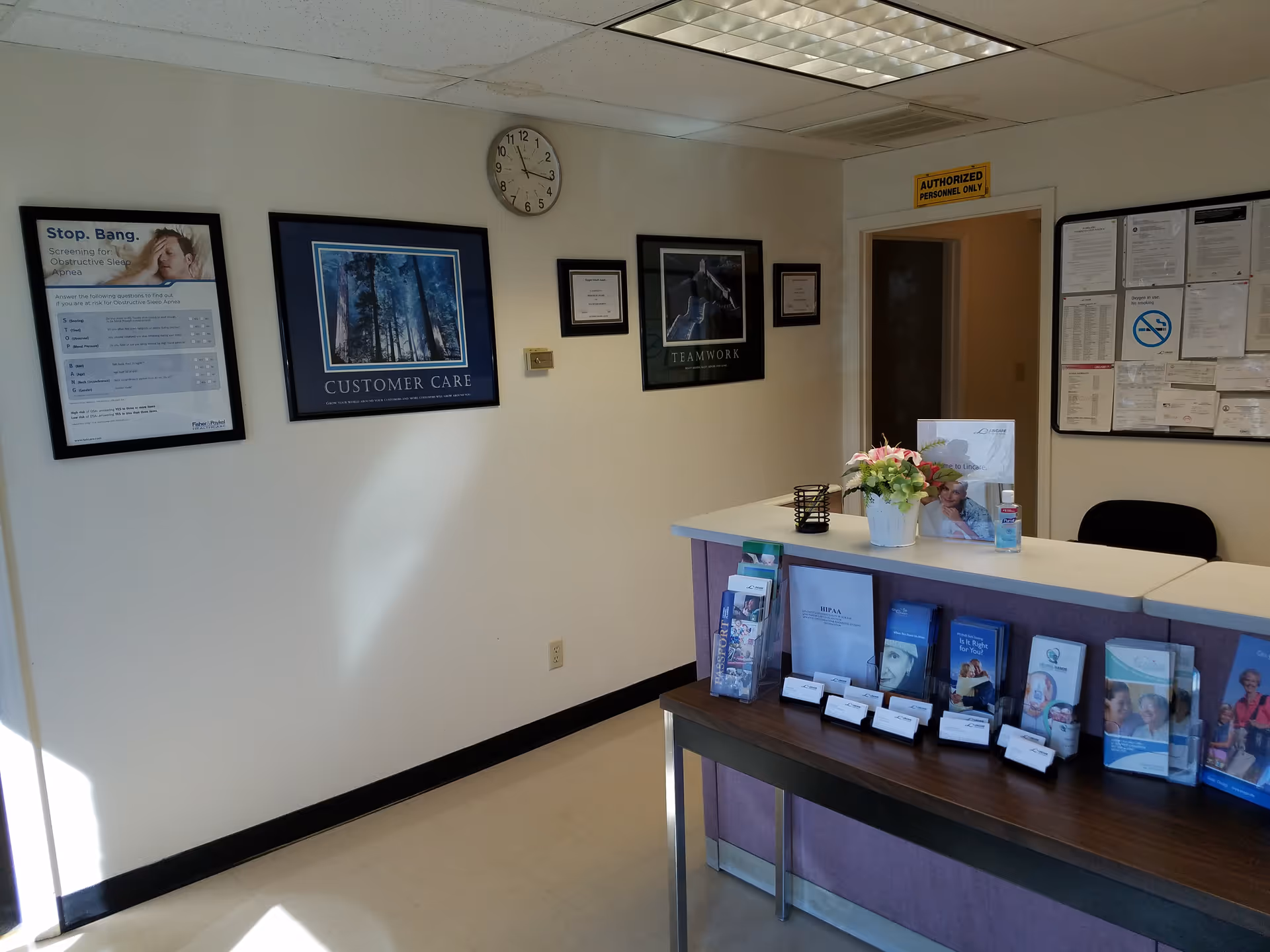 Reception lobby at LINCARE with front desk, brochures, wall art, and a clock.
