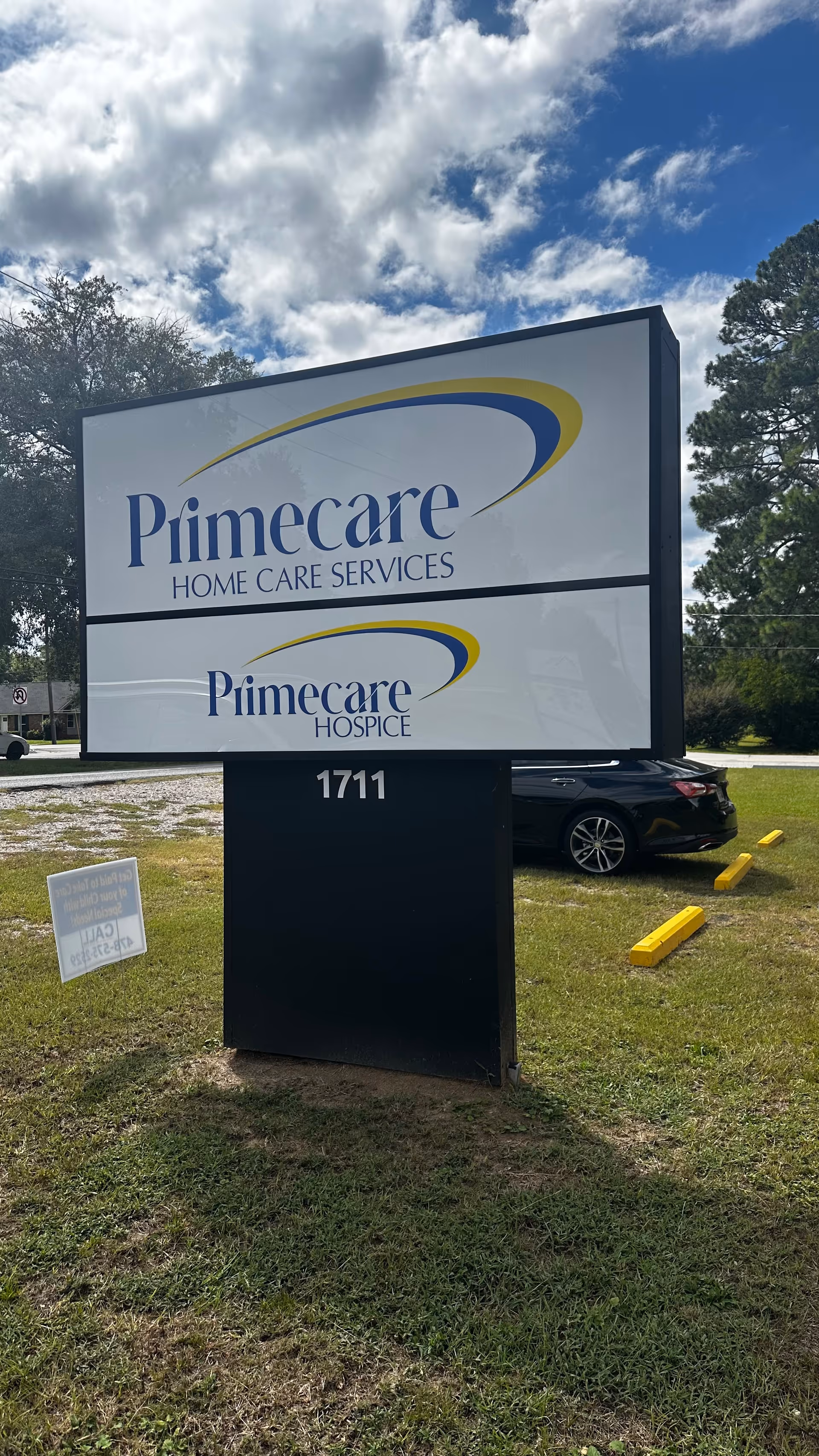 A Primecare Home Care Services sign on a grassy lot under a blue sky.