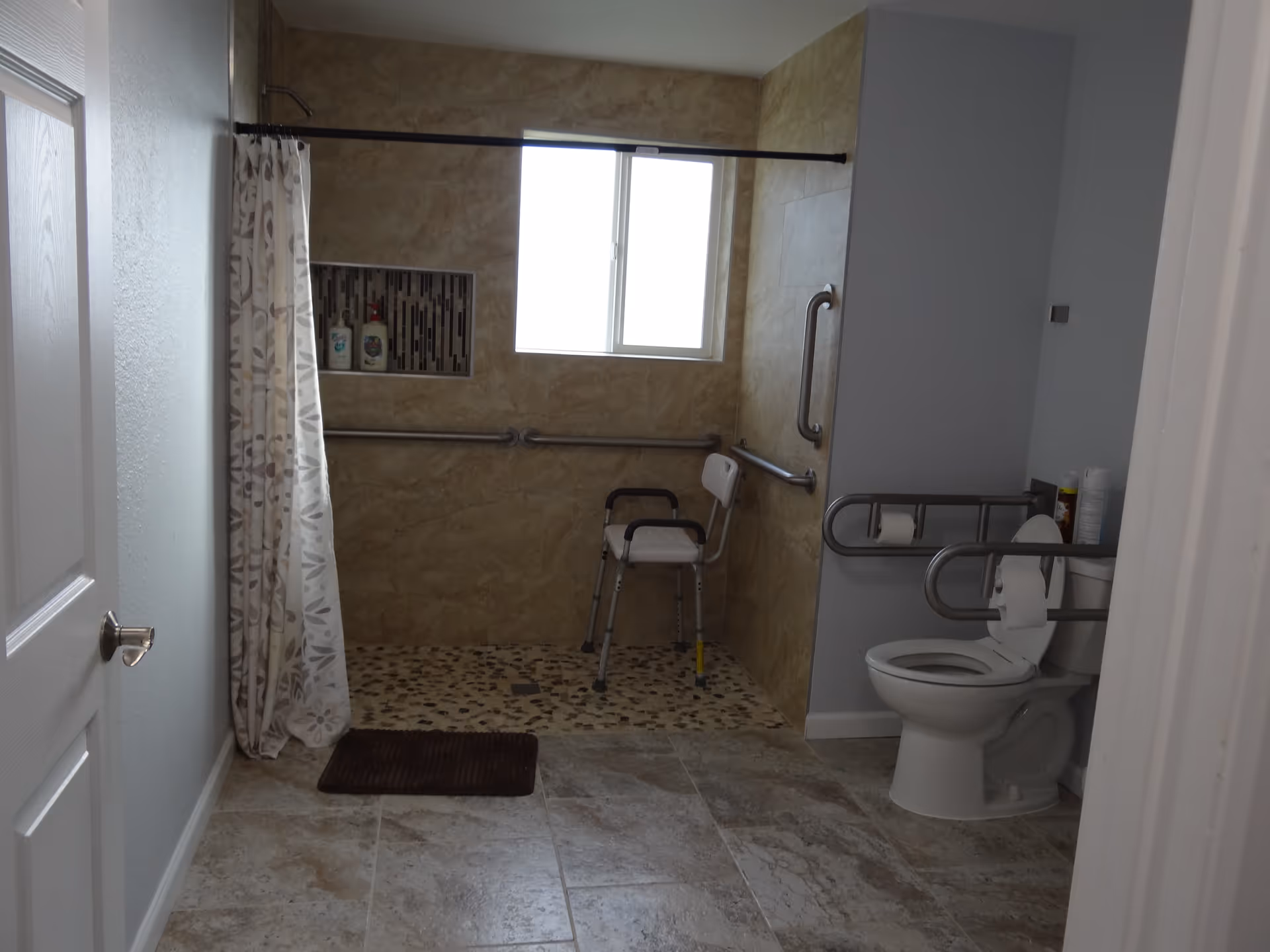Accessible bathroom with shower, grab bars, and toilet in a senior facility.