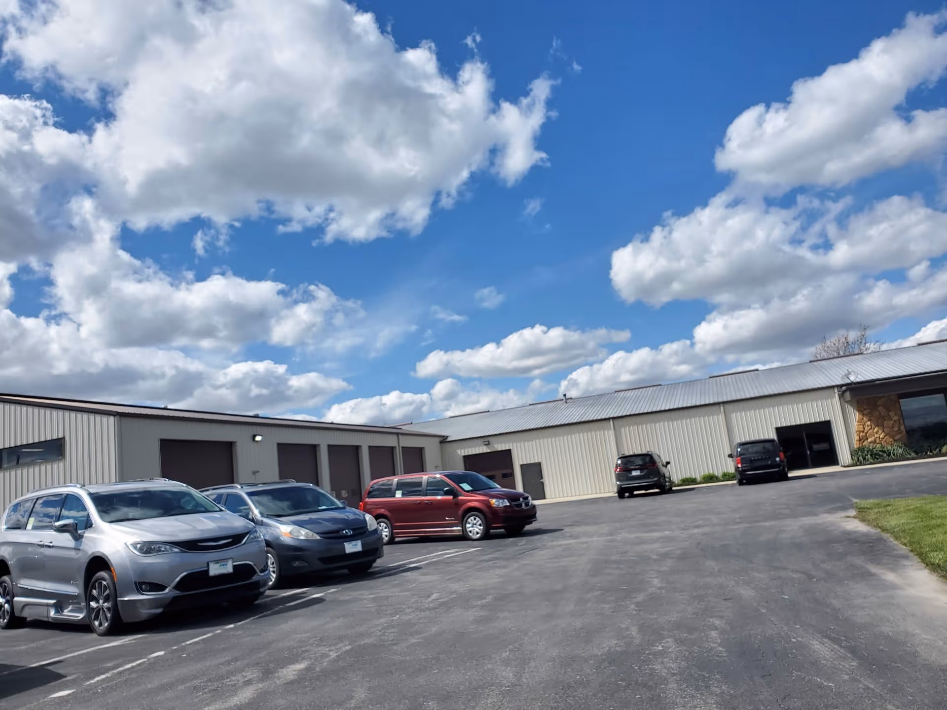 Exterior view of MobilityWorks facility with parked cars and a blue sky.
