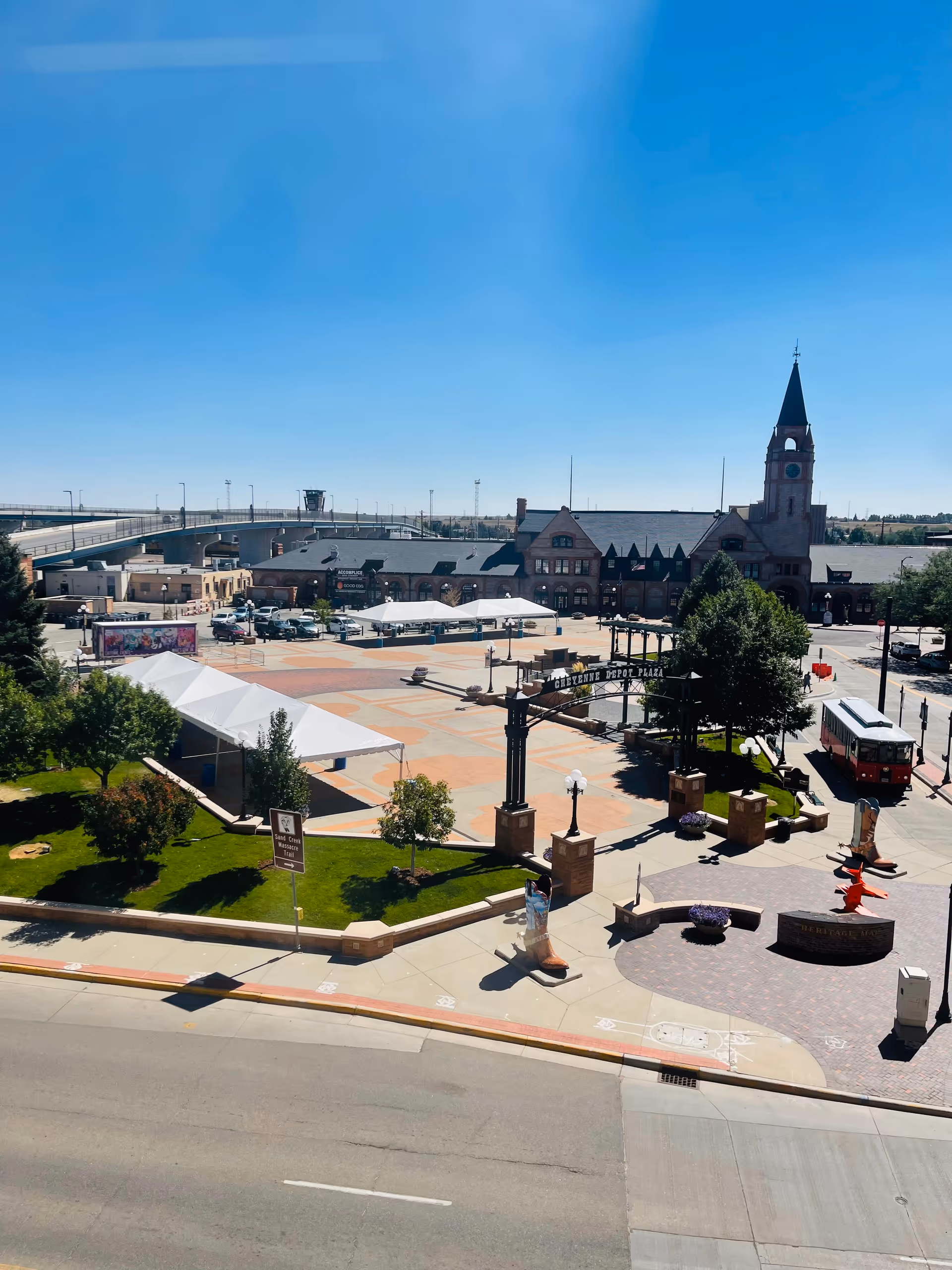 A spacious outdoor plaza in front of a brick complex with tents and a clock tower.