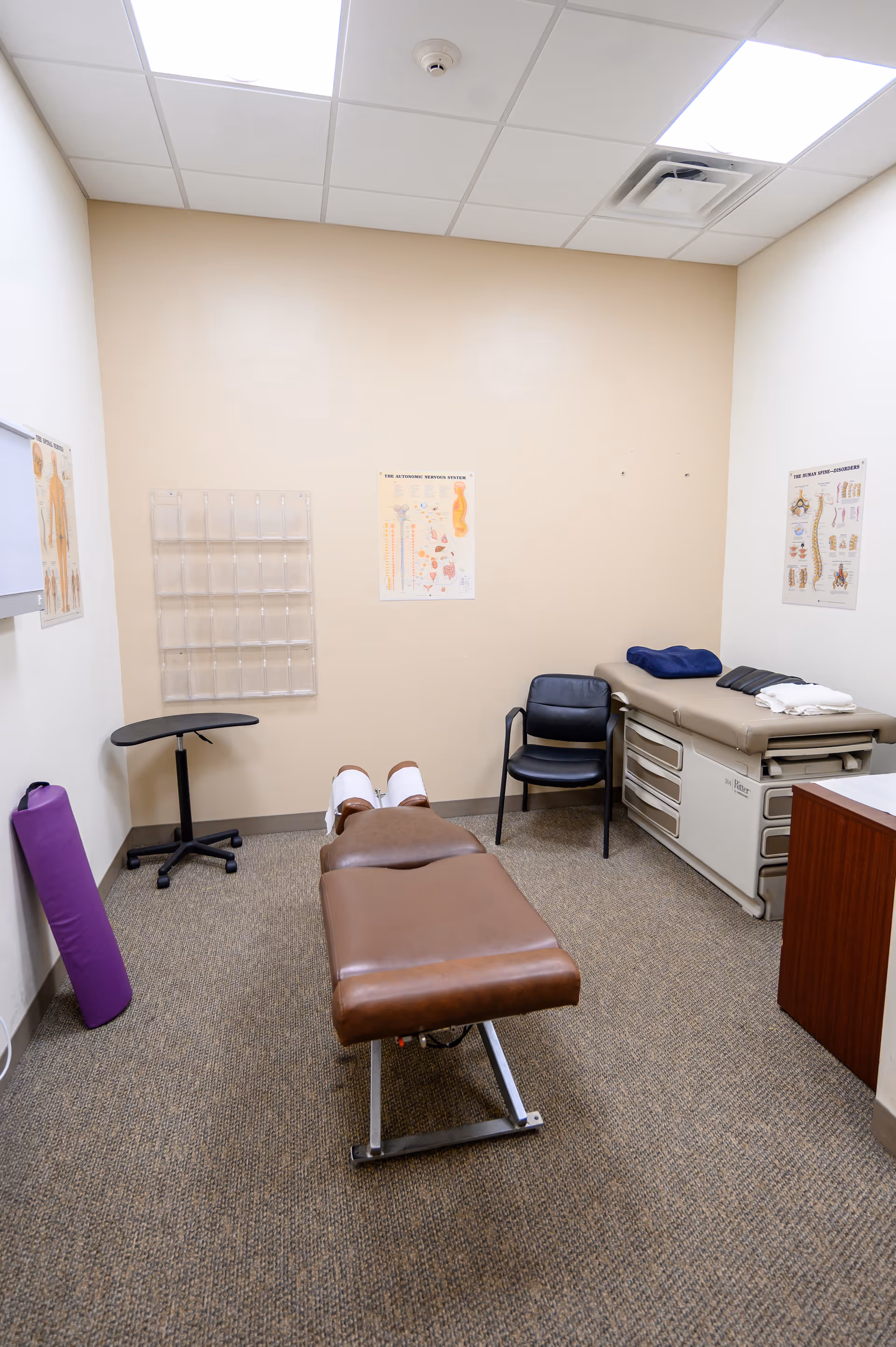Therapy room in a senior facility with examination table and medical posters.
