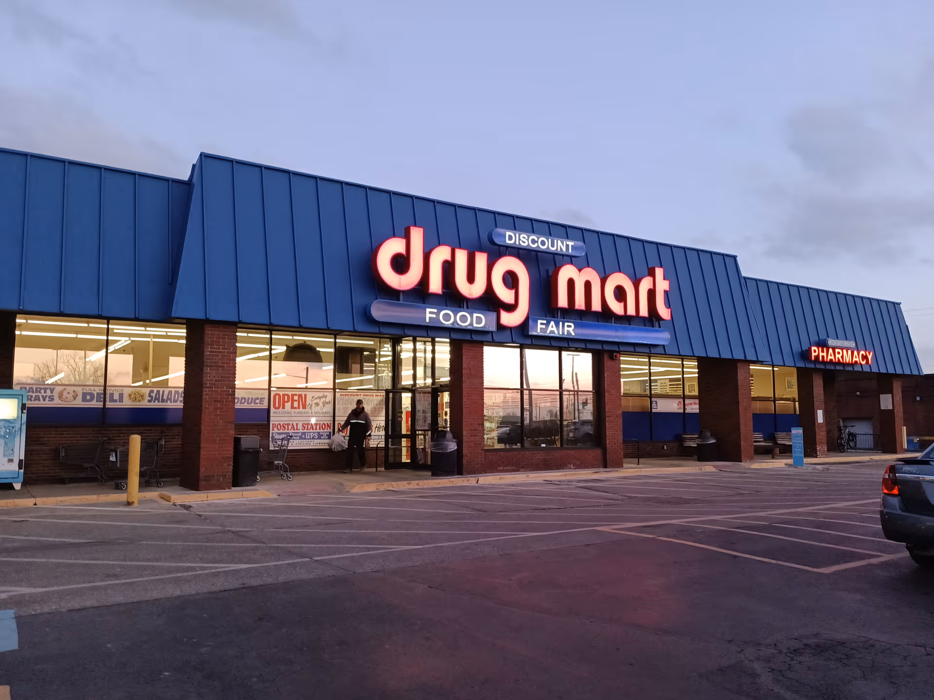 Exterior view of a discount drugstore with a large illuminated drug mart sign.
