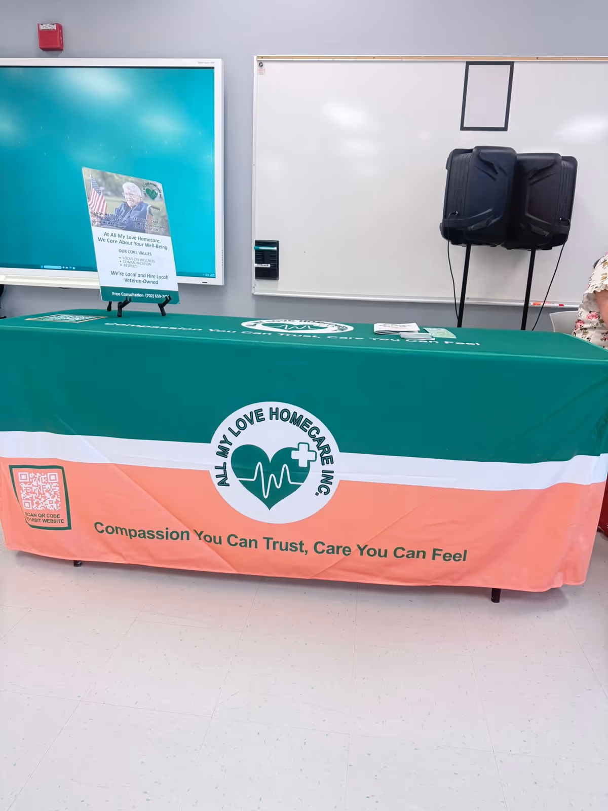 Table with green and orange All My Love Homecare banner in a classroom-like room.