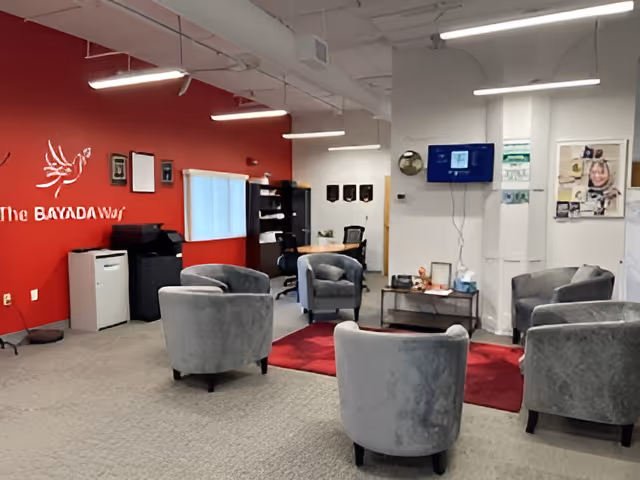 Lobby seating area at BAYADA Pediatrics featuring gray chairs, red wall, and a TV.