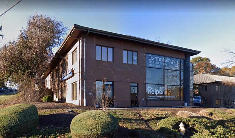 Brick office building labeled Senior Helpers and Dermatology with large windows and a landscaped front yard.