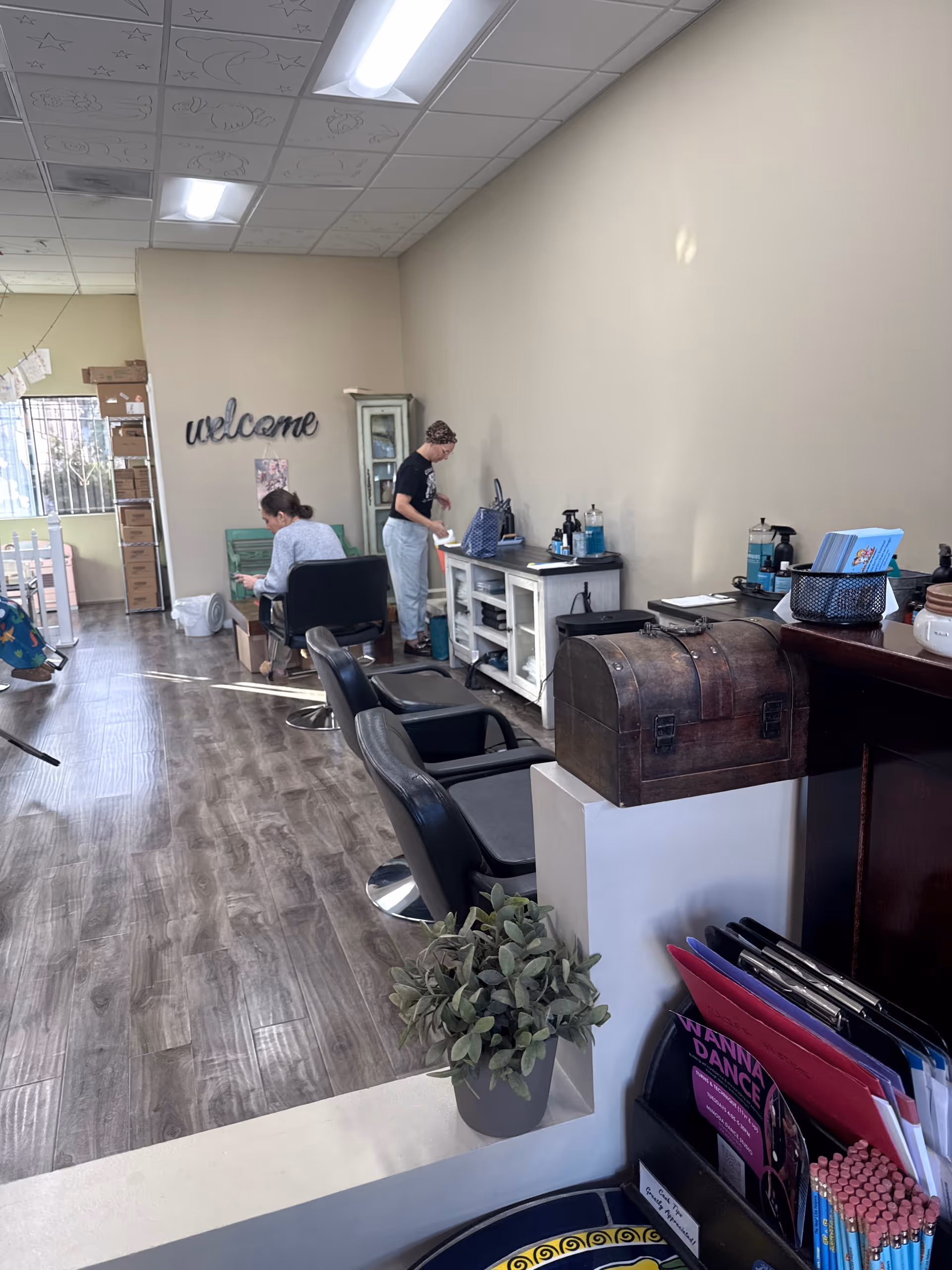 Inside a bright salon area with chairs, counter, and two staff members assisting a resident.