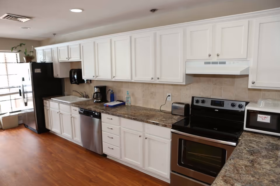 White cabinets, stainless appliances, and granite countertops line a bright kitchen.