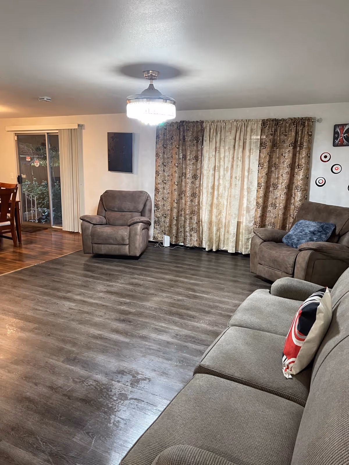 A living room with brown couches, a recliner, and patterned curtains.