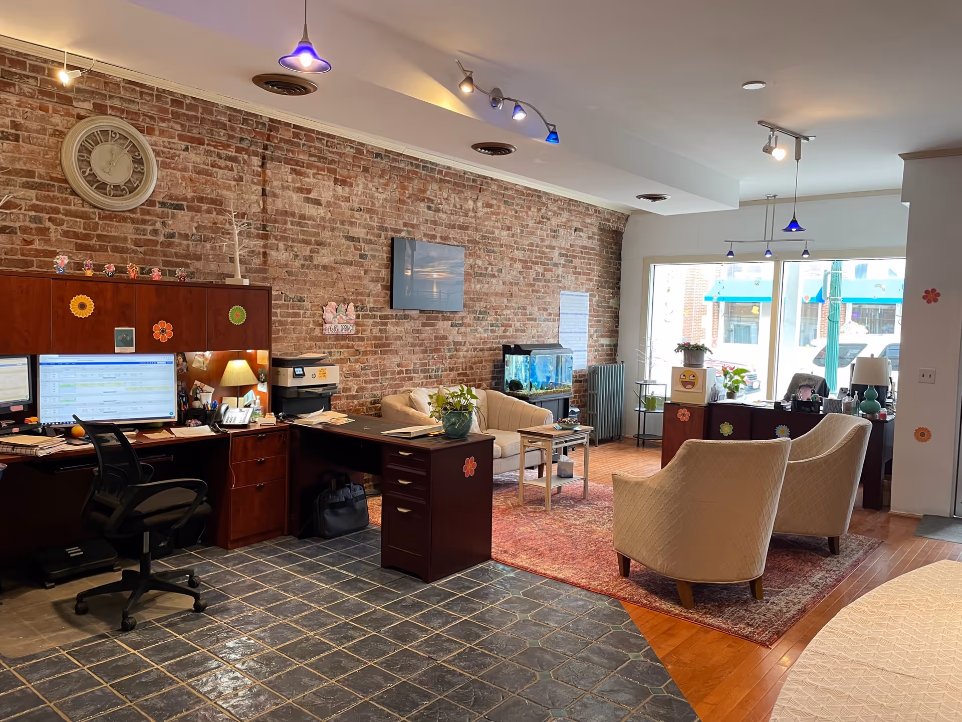 Lobby area with brick wall, desks, computers, fish tank, and seating.