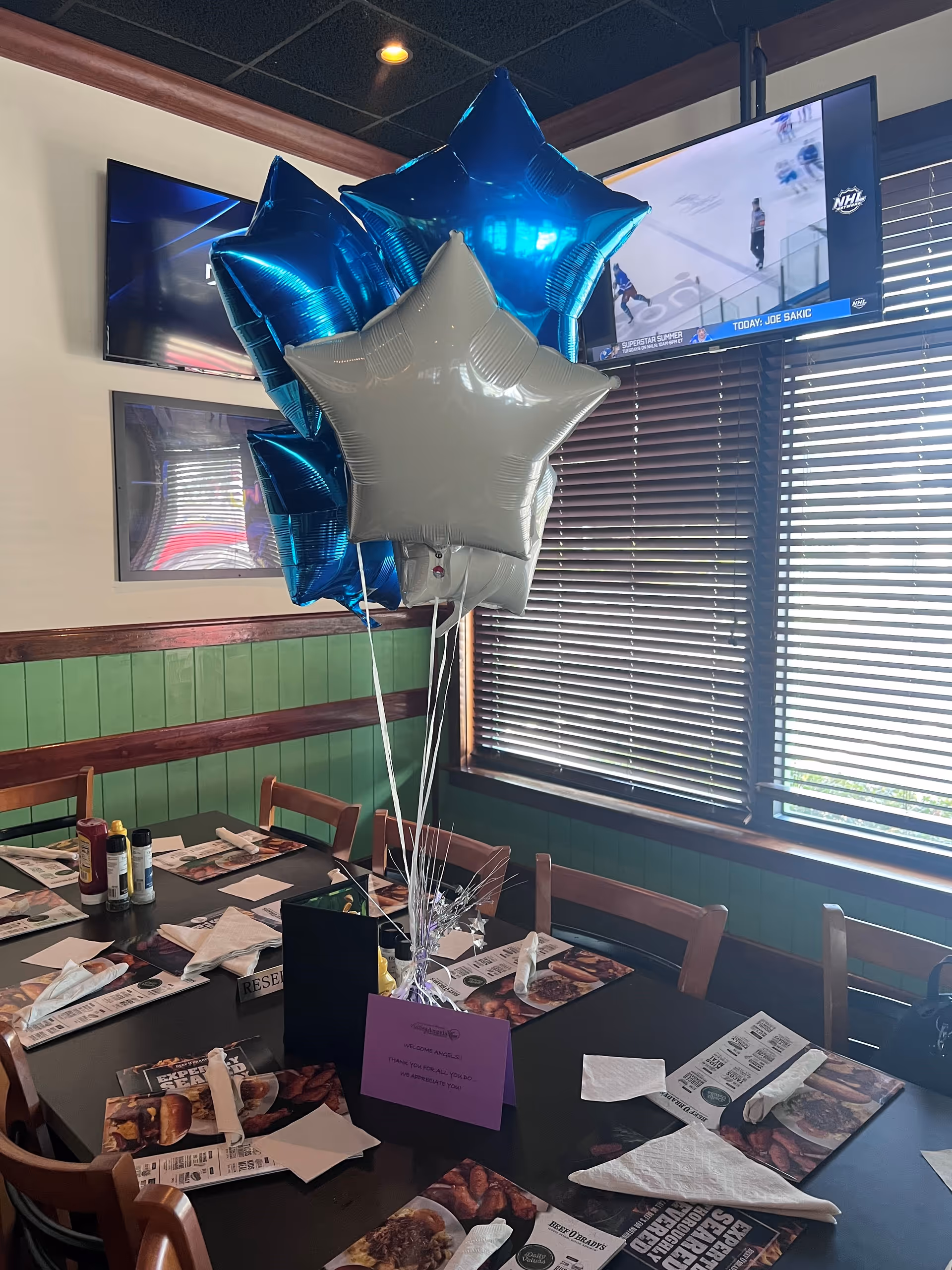 Dining table set with utensils and blue and silver star balloons in a dining area.