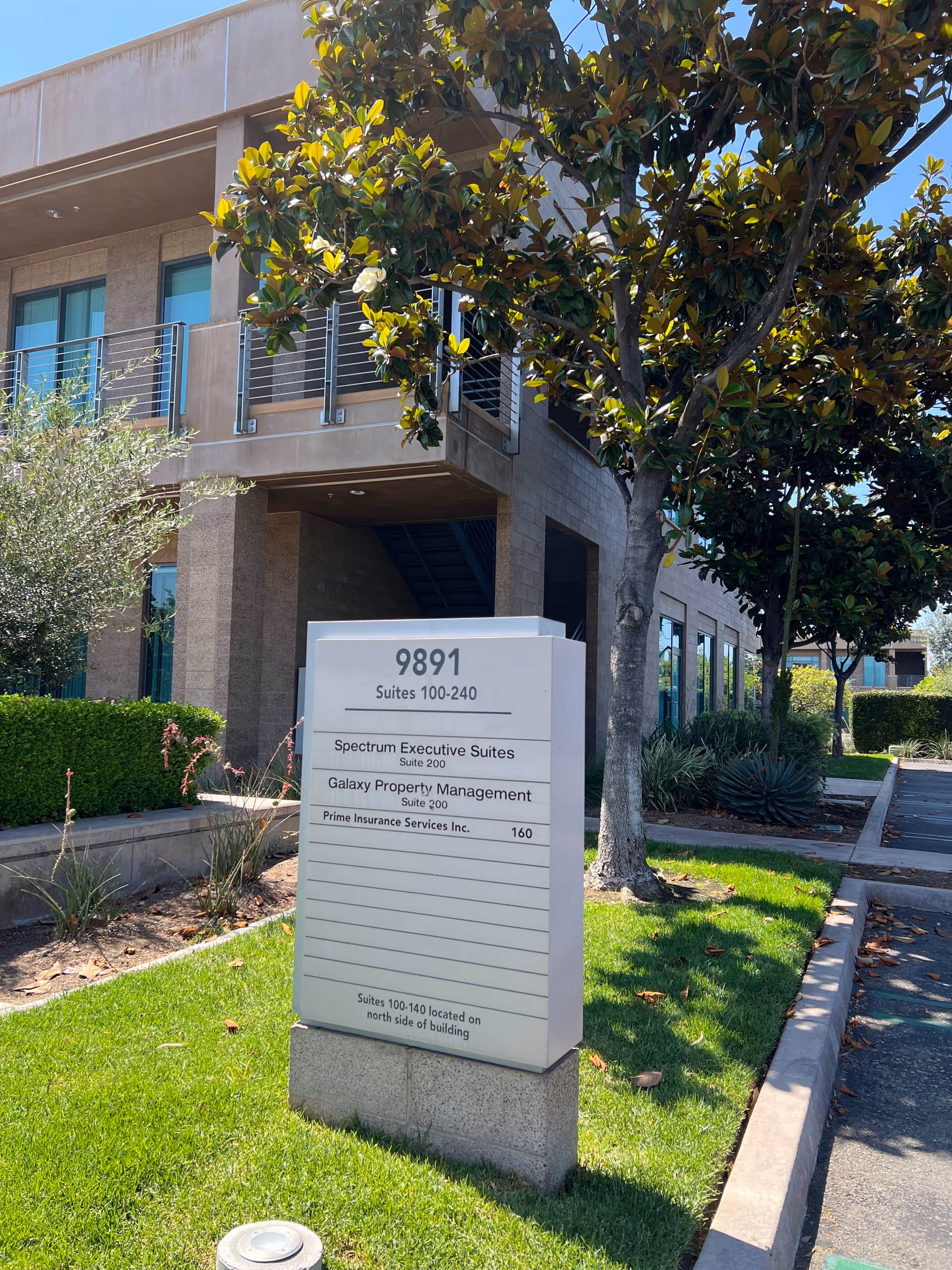 Exterior view of a senior living facility with a sign and landscaped surroundings.
