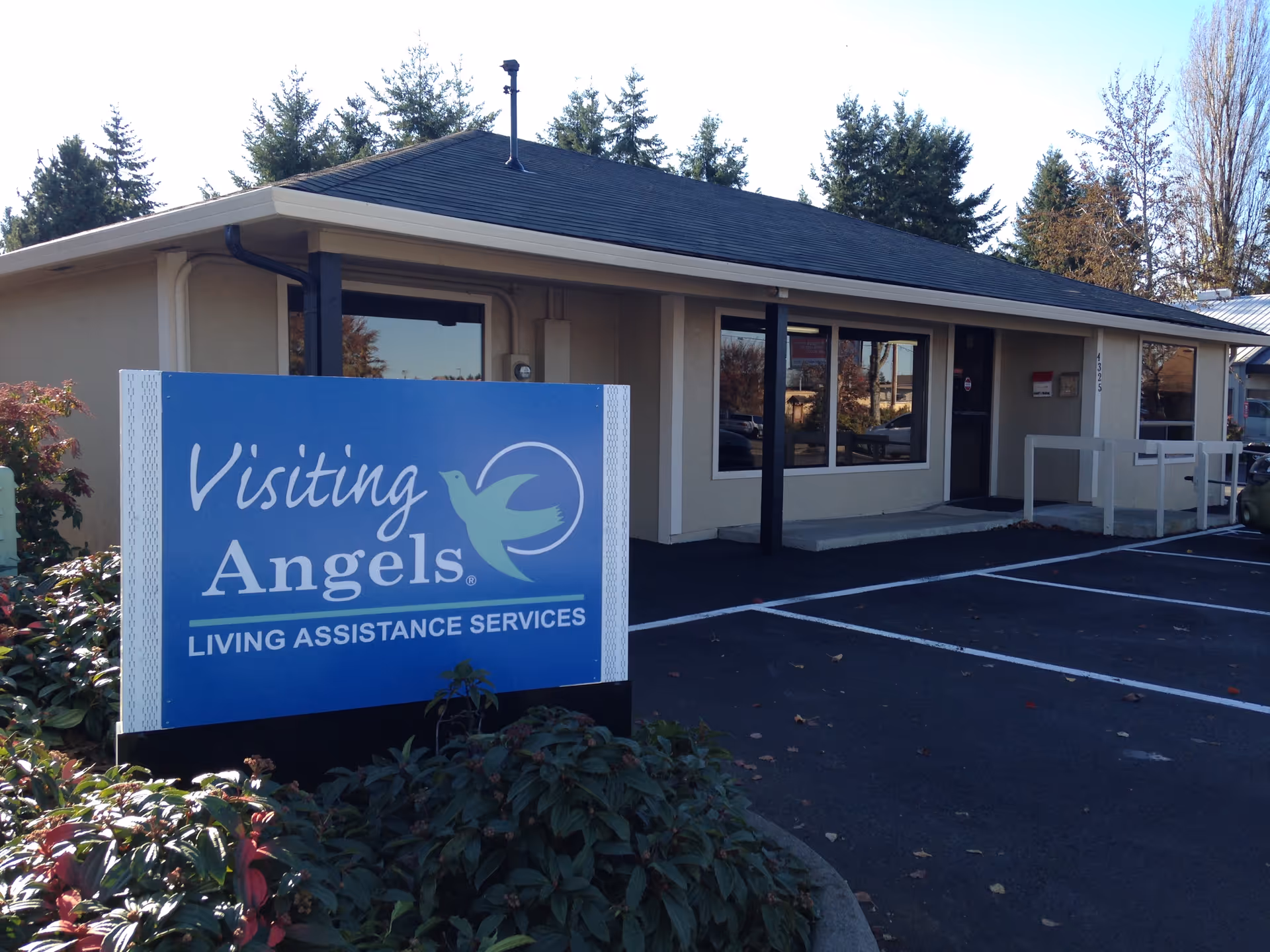 Front view of a Visiting Angels building with a large blue sign in the parking lot