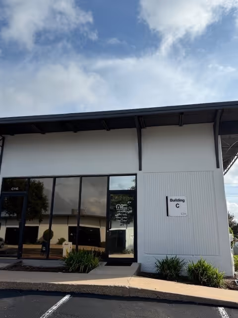 Exterior view of a modern building entrance with glass doors and a Building C sign.