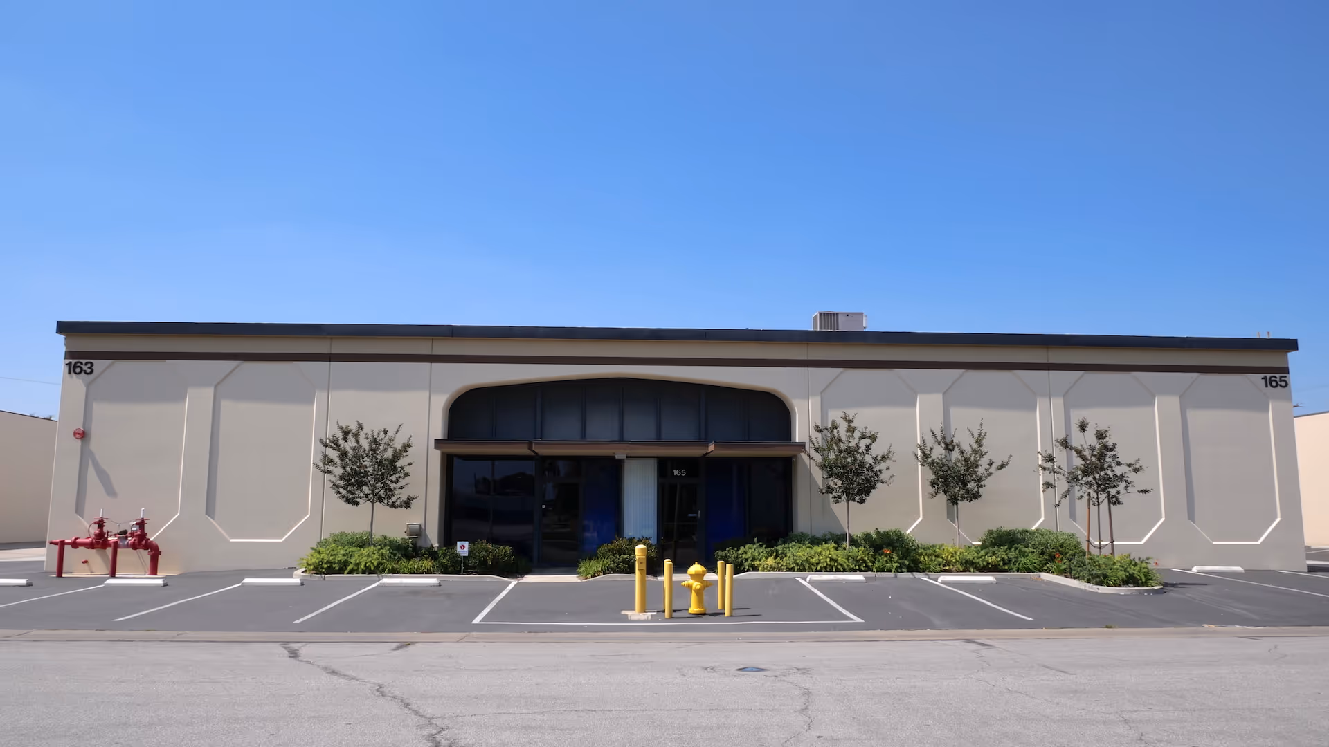 Front exterior of a senior living facility with glass entrance and parking.