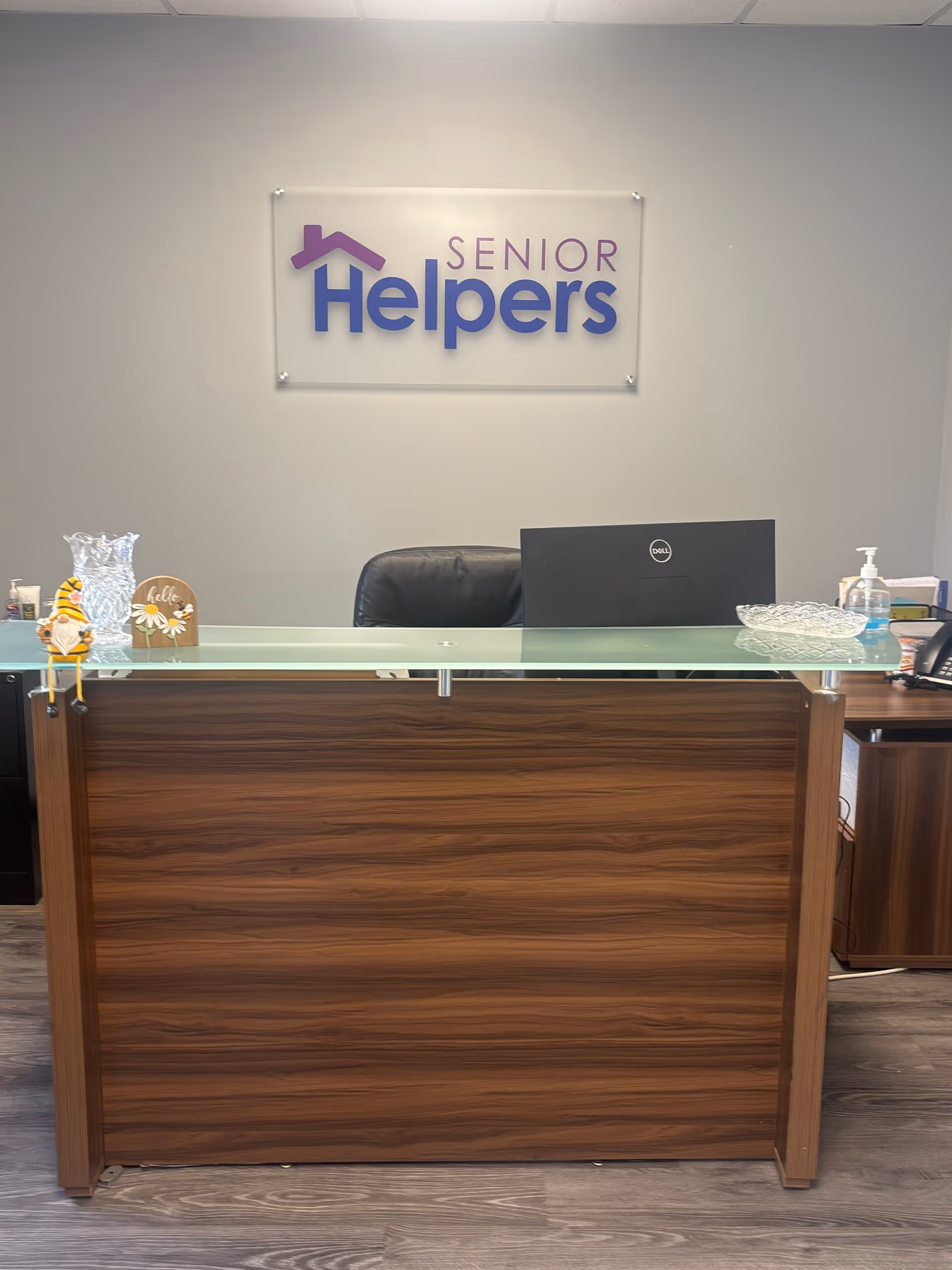 Reception desk in a Senior Helpers lobby with a sign on the wall.