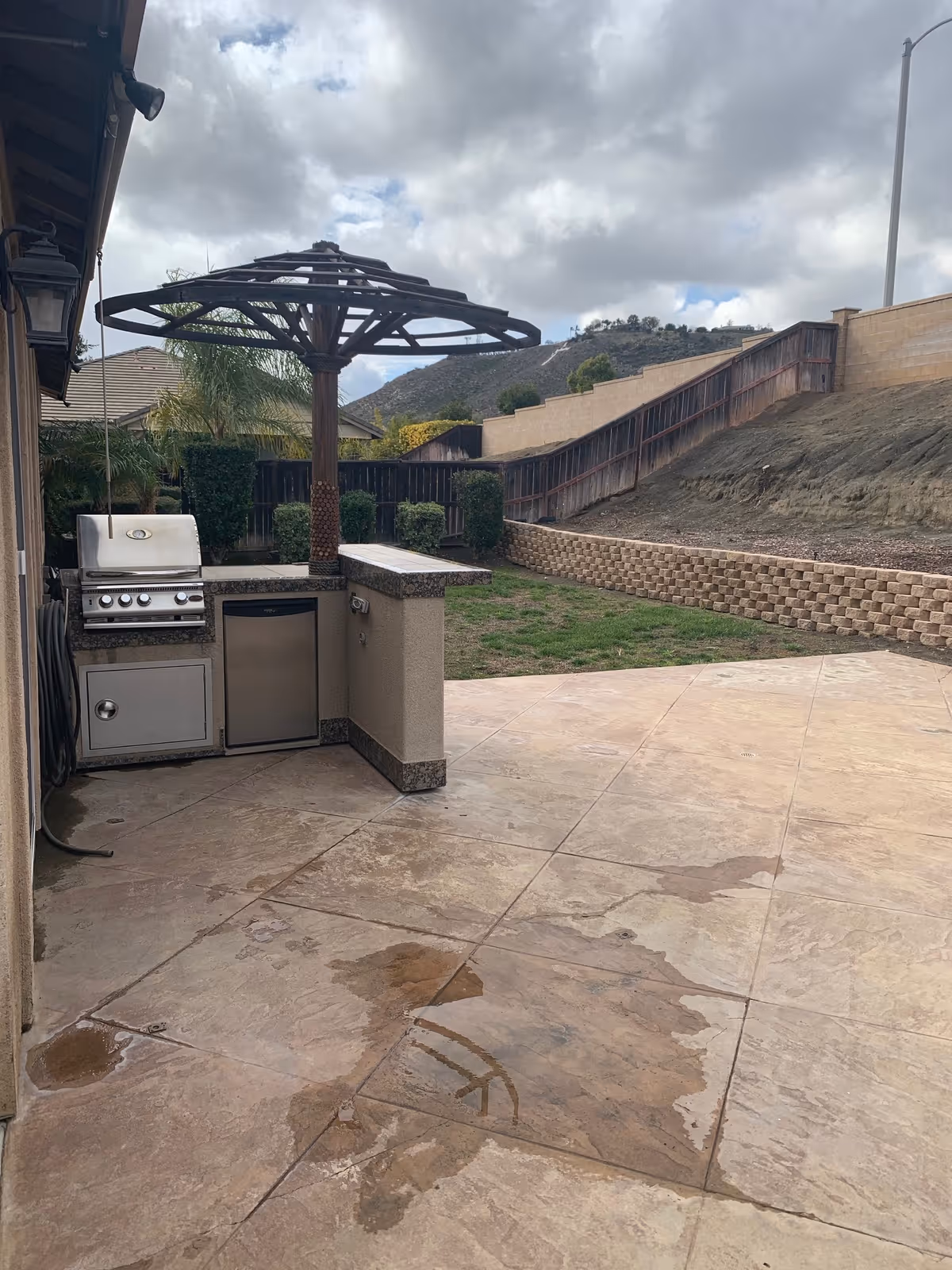 Outdoor patio features a built-in grill, sink, counter, and circular umbrella structure.
