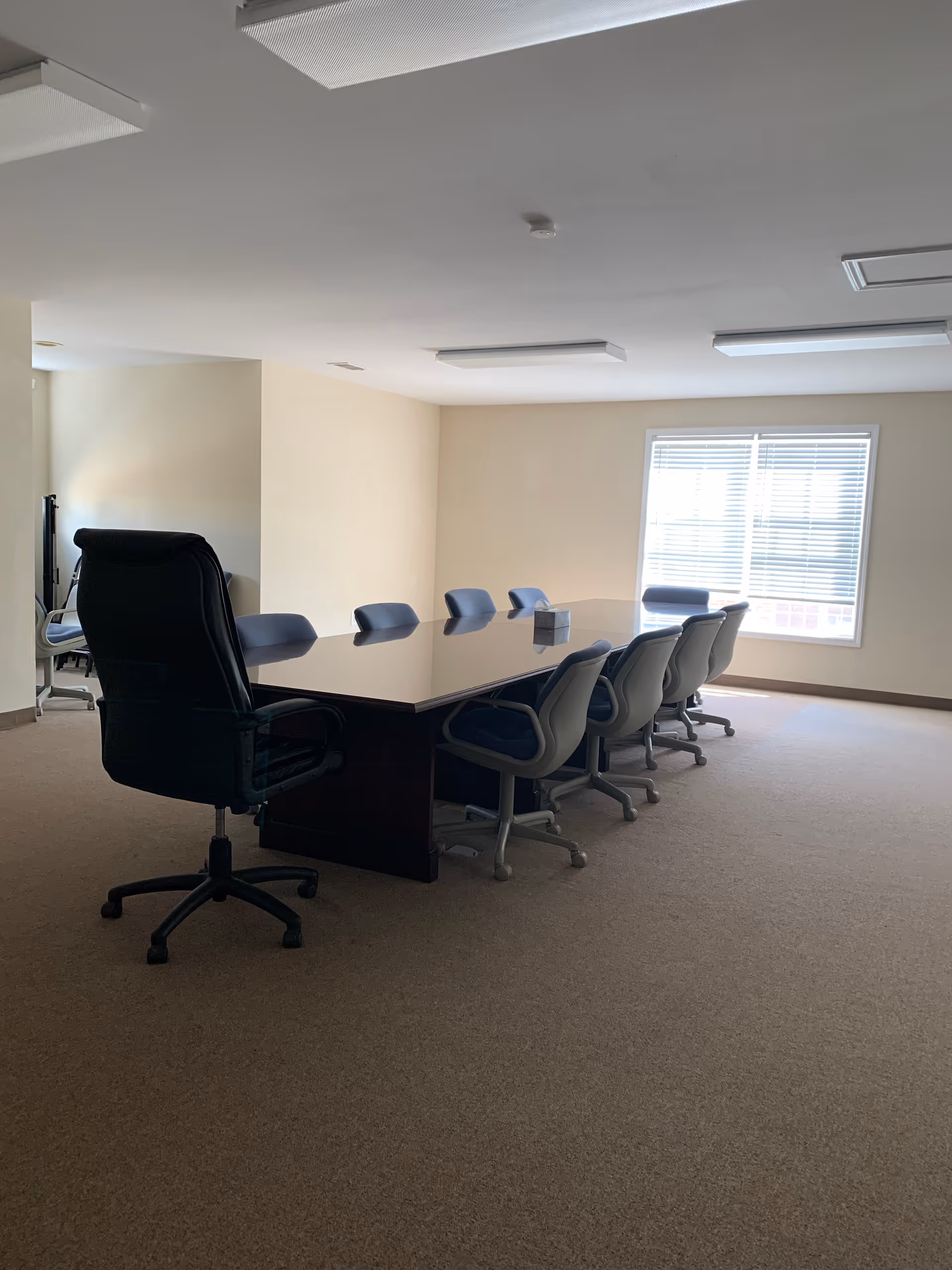 Sunlit beige senior living facility meeting room with a long conference table.