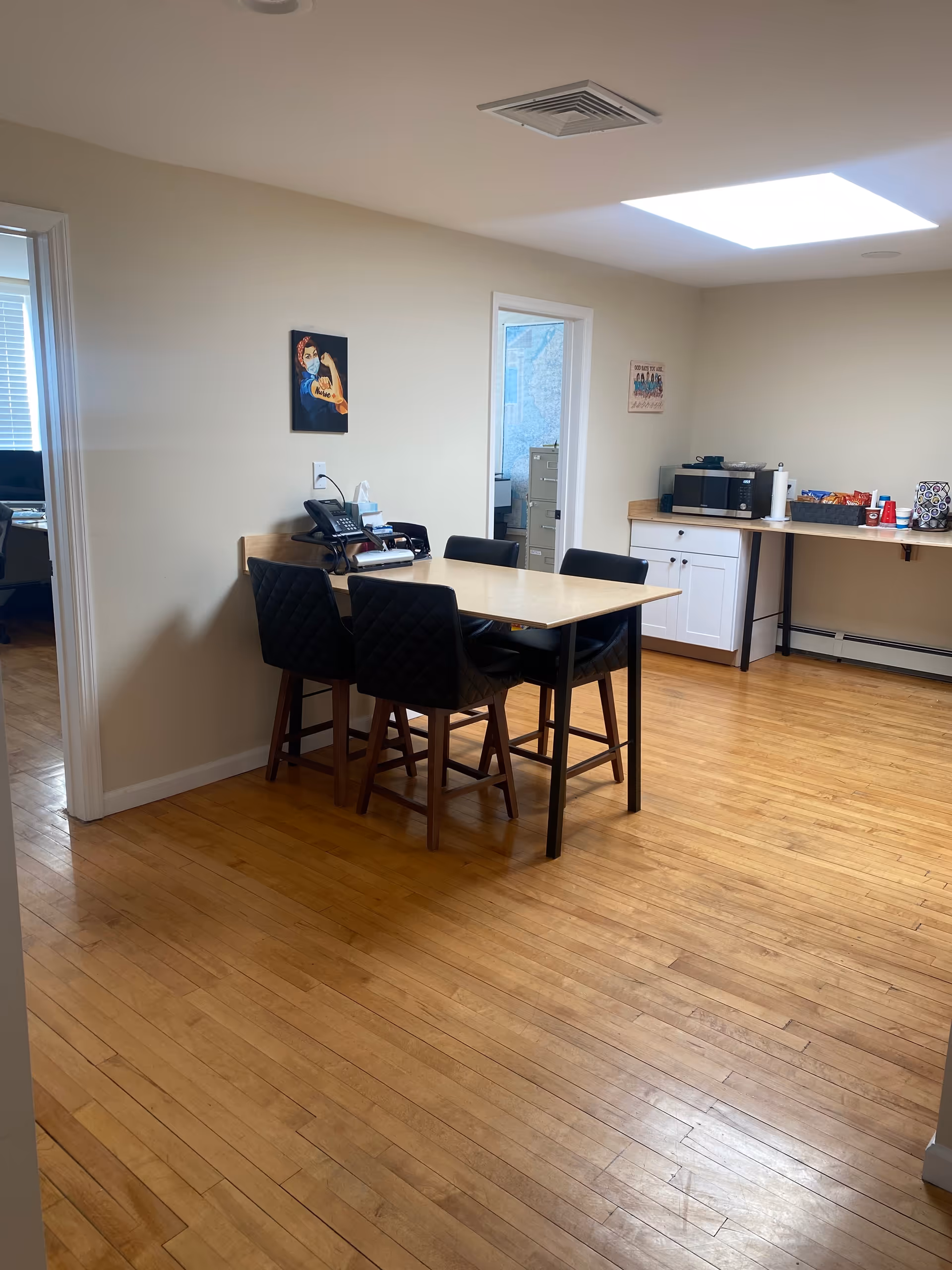 A dining area with a wooden table and black chairs in a bright room.
