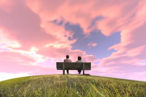Two people sit on a bench on a grassy hill beneath a pink sunset sky.