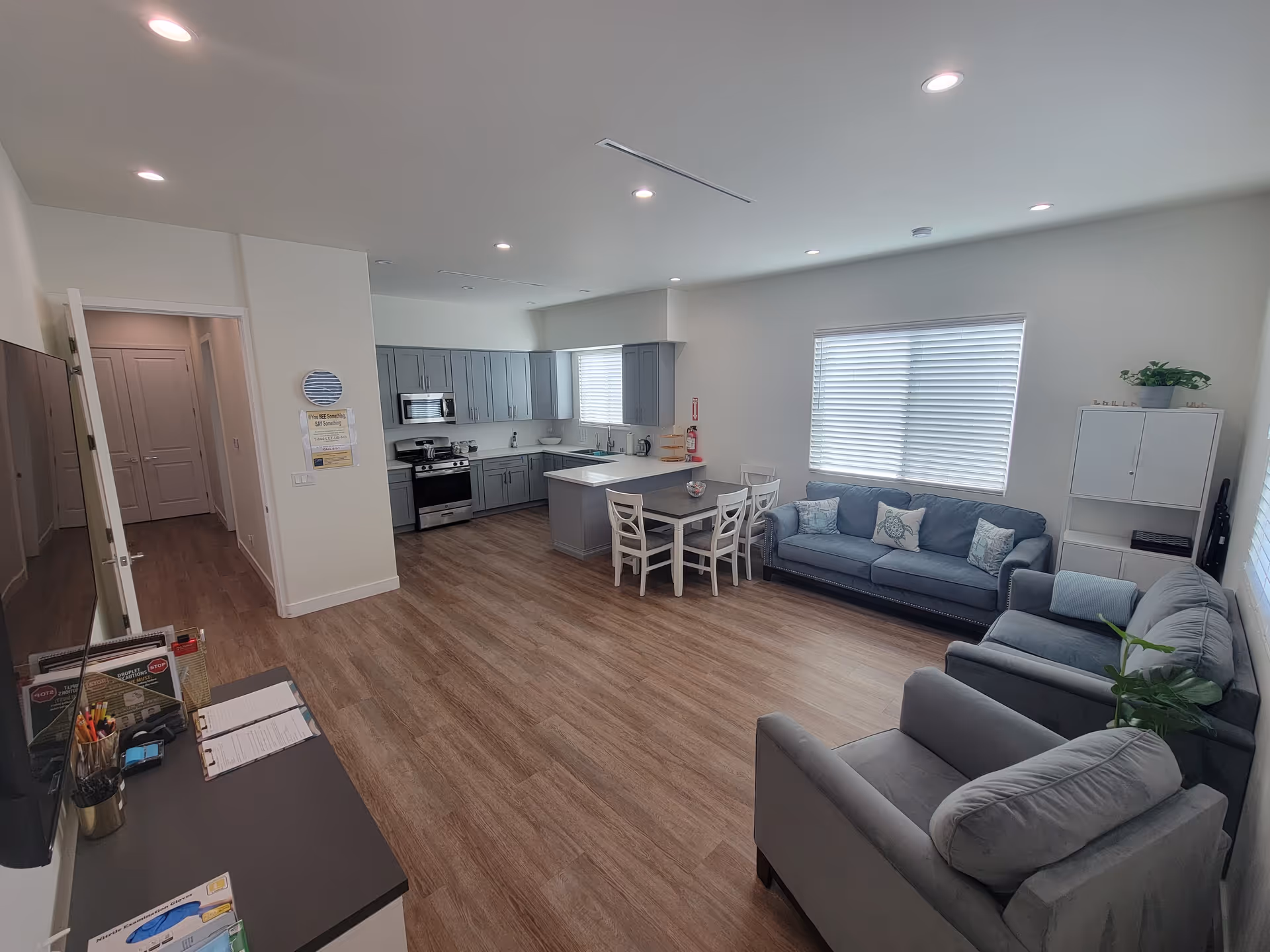 Open-concept living area with gray sofas, dining table, and a modern kitchen.