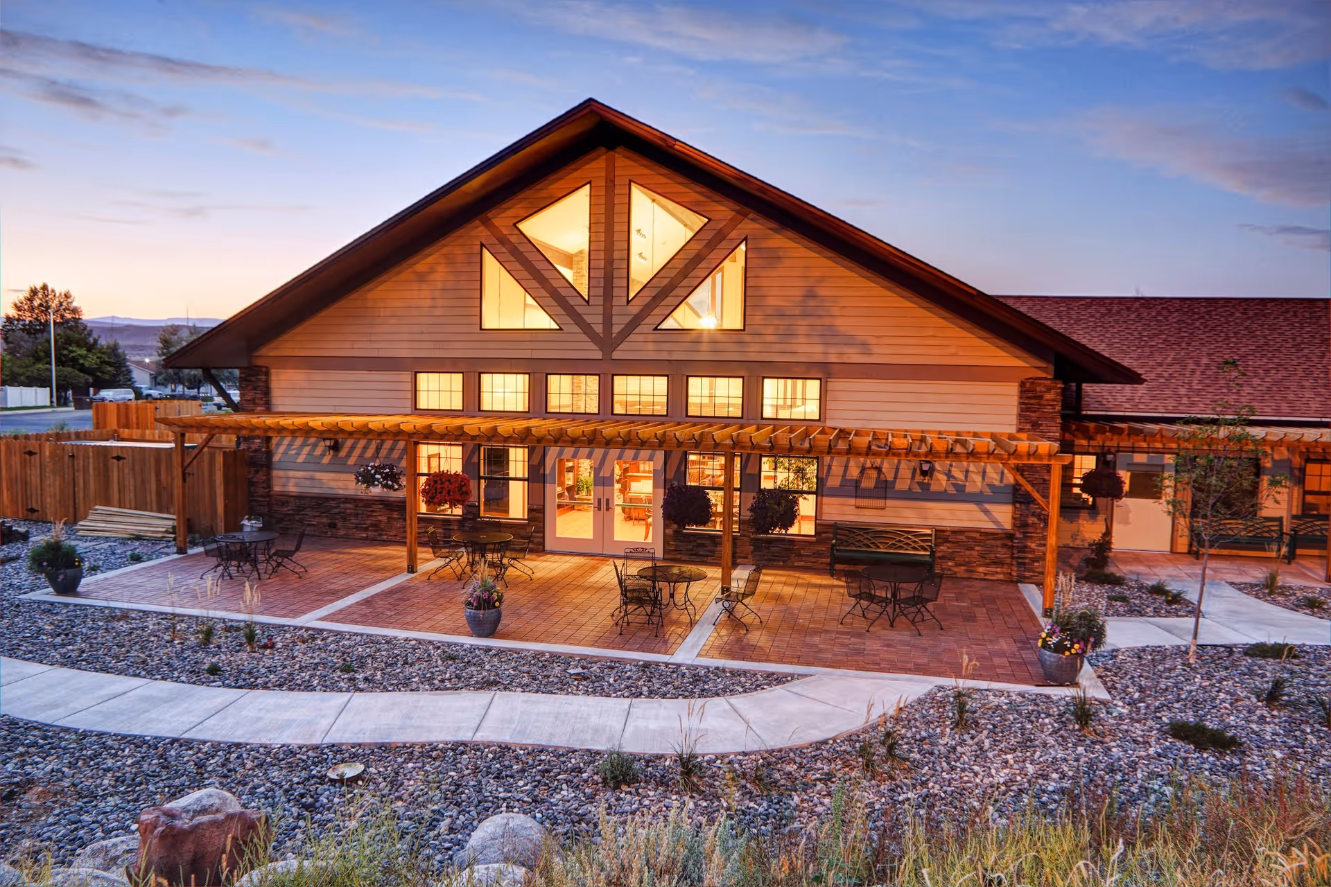Lodge-style senior living facility exterior with covered patio and outdoor seating.