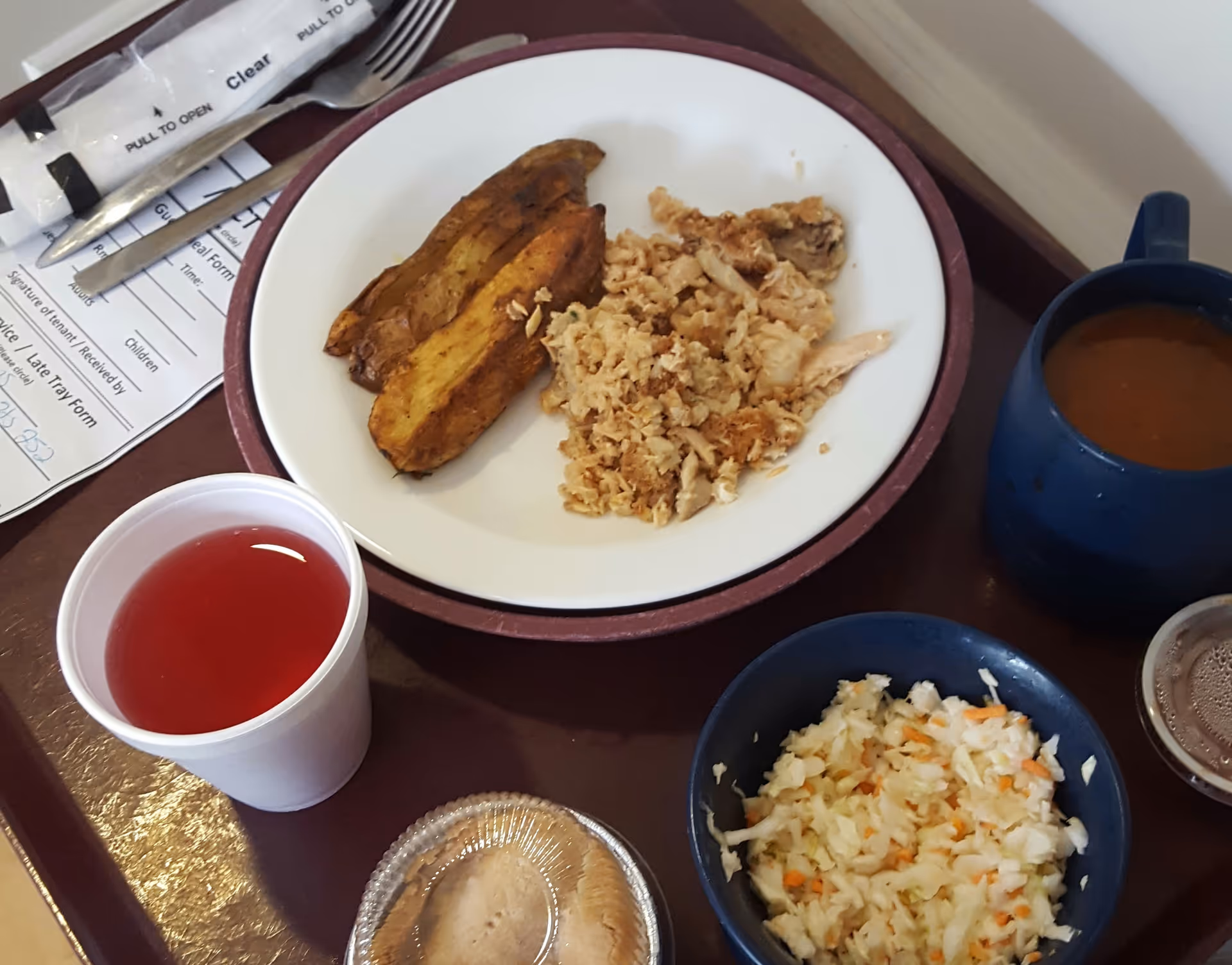 Meal tray features a plate with meat and stuffing, cabbage slaw, juice, and soup.