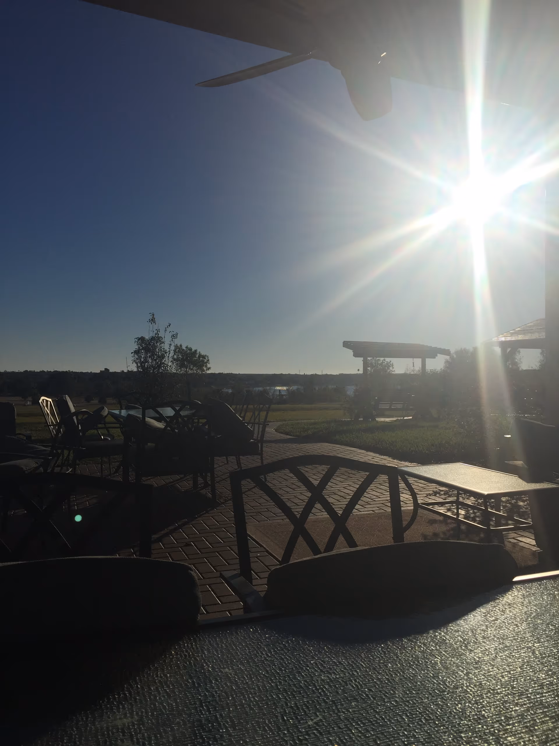 Sunny outdoor patio with metal chairs and tables overlooking open landscape.